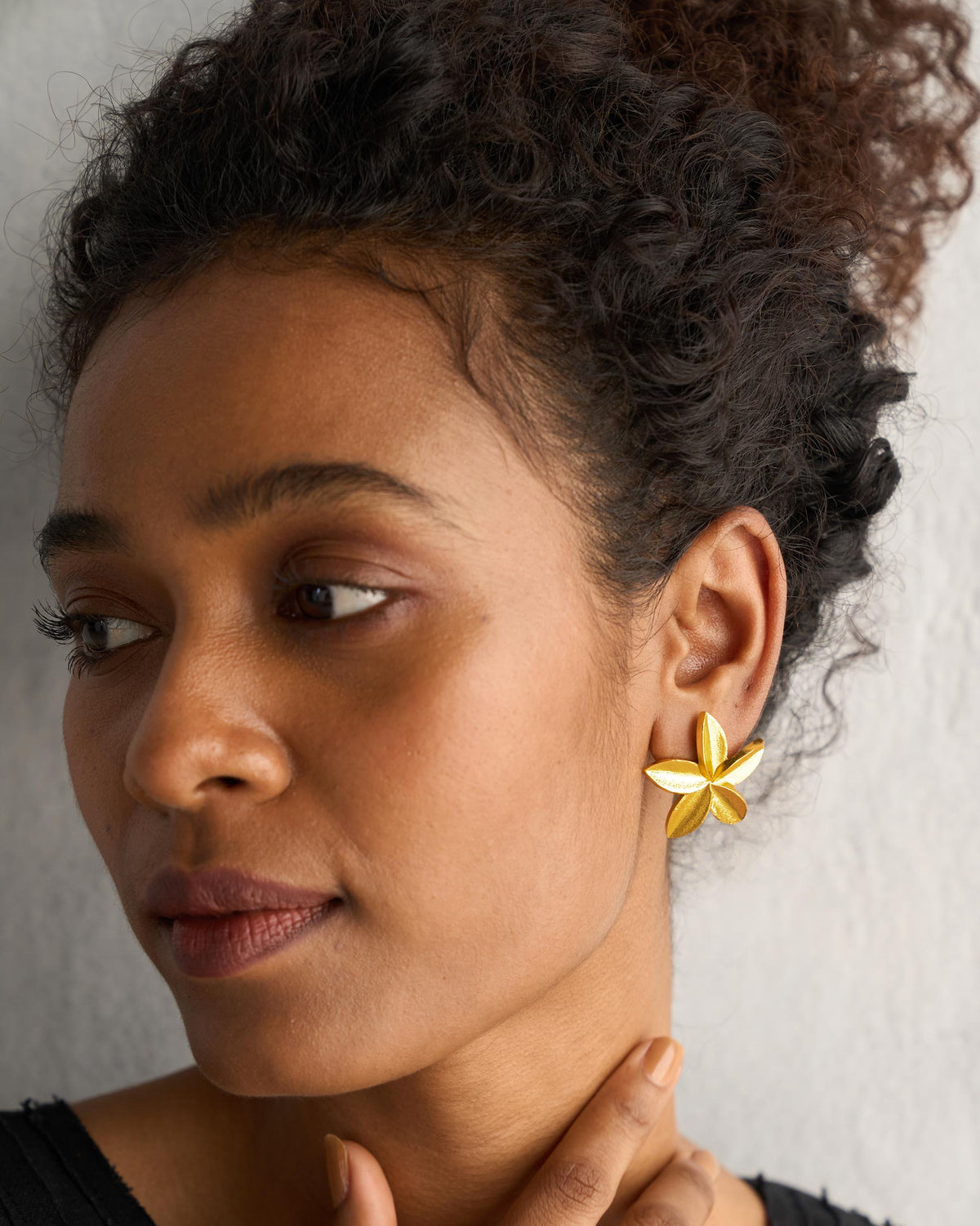Close-up of a gold Frangi Stud showing its five-petal flower shape.