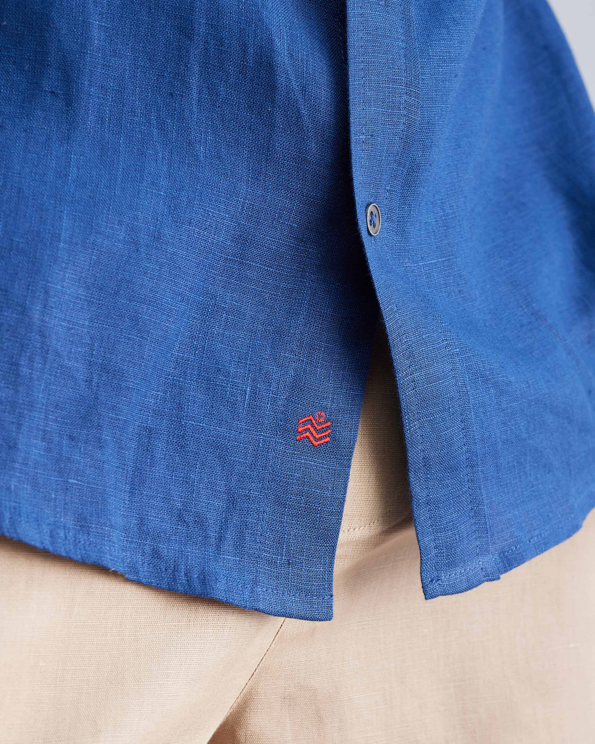 Close-up of the red logo near the hem of a navy Half Sleeve Shirt.