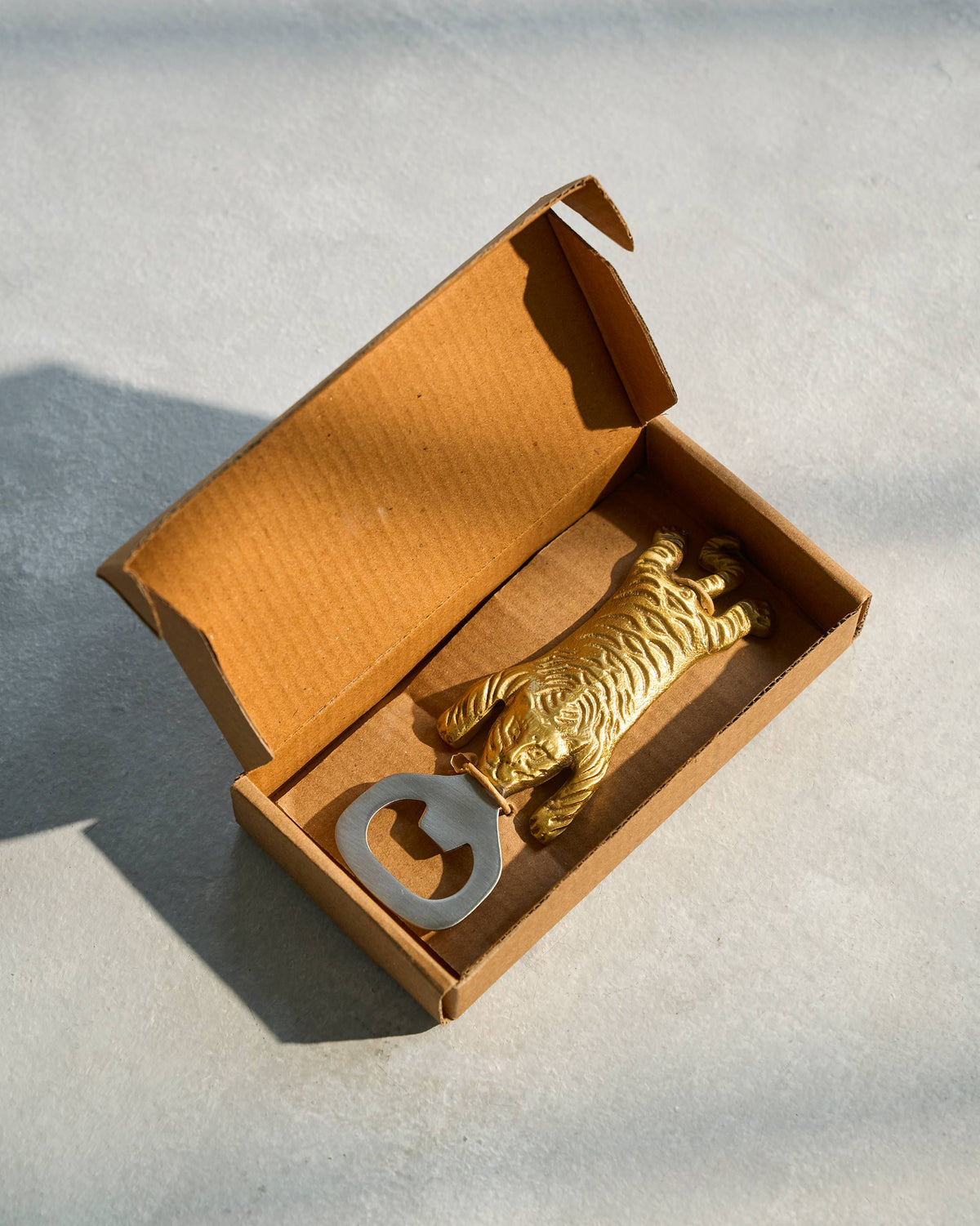 Gold Sumatran tiger bottle opener inside an open gift box.