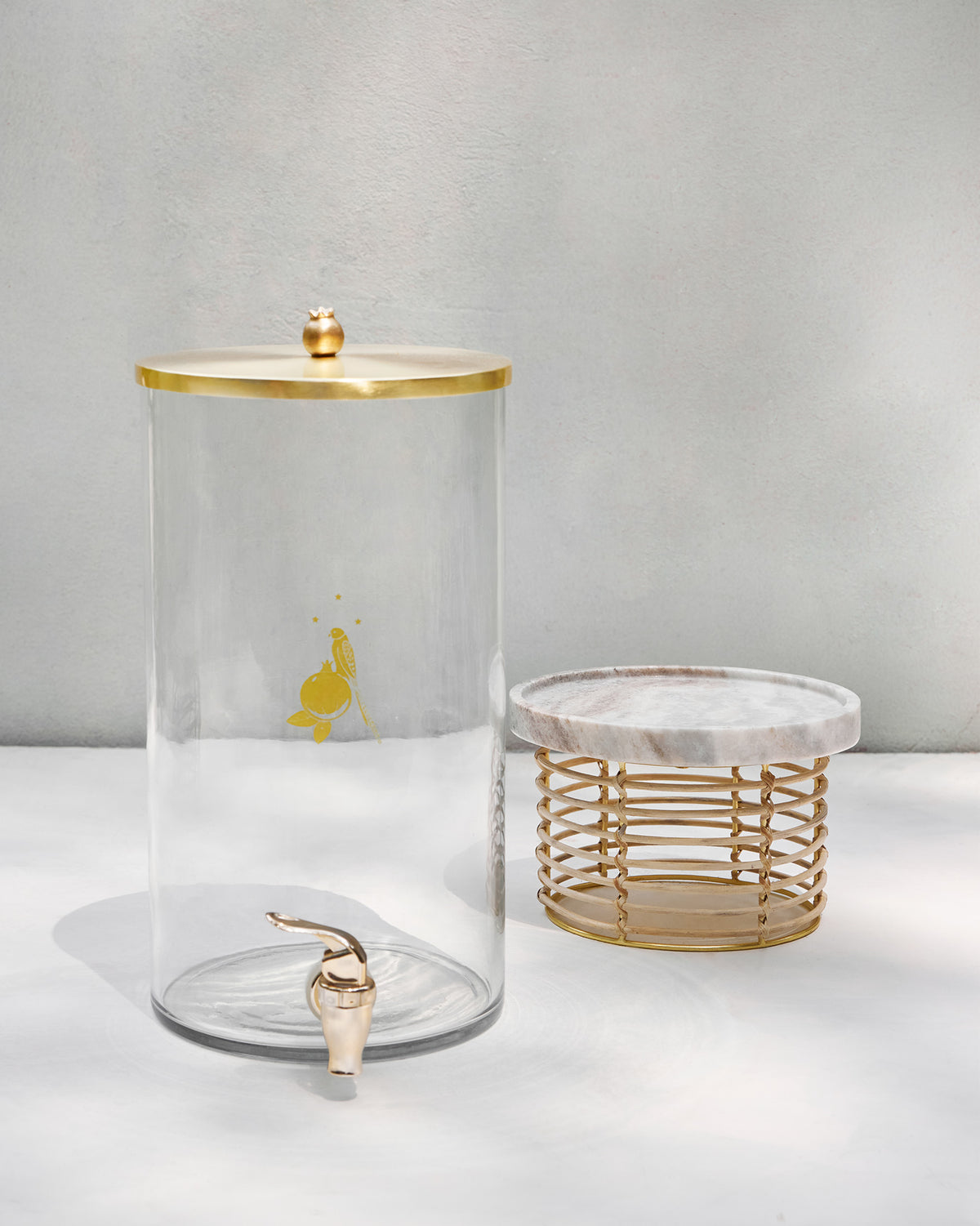Mistle dispenser with gold lid beside its marble and gold wire stand.