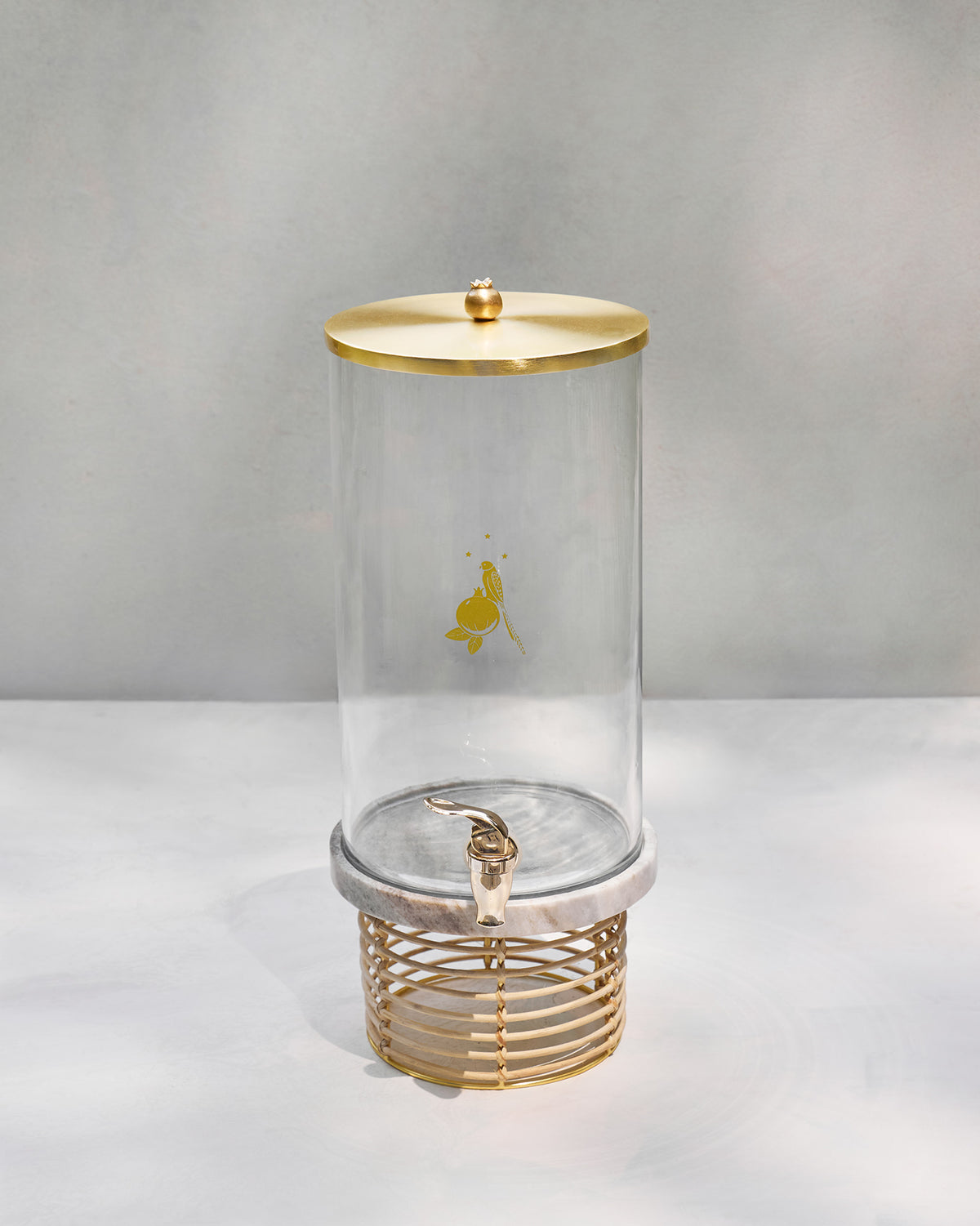 Tall Mistle glass dispenser assembled on a marble and rattan stand.