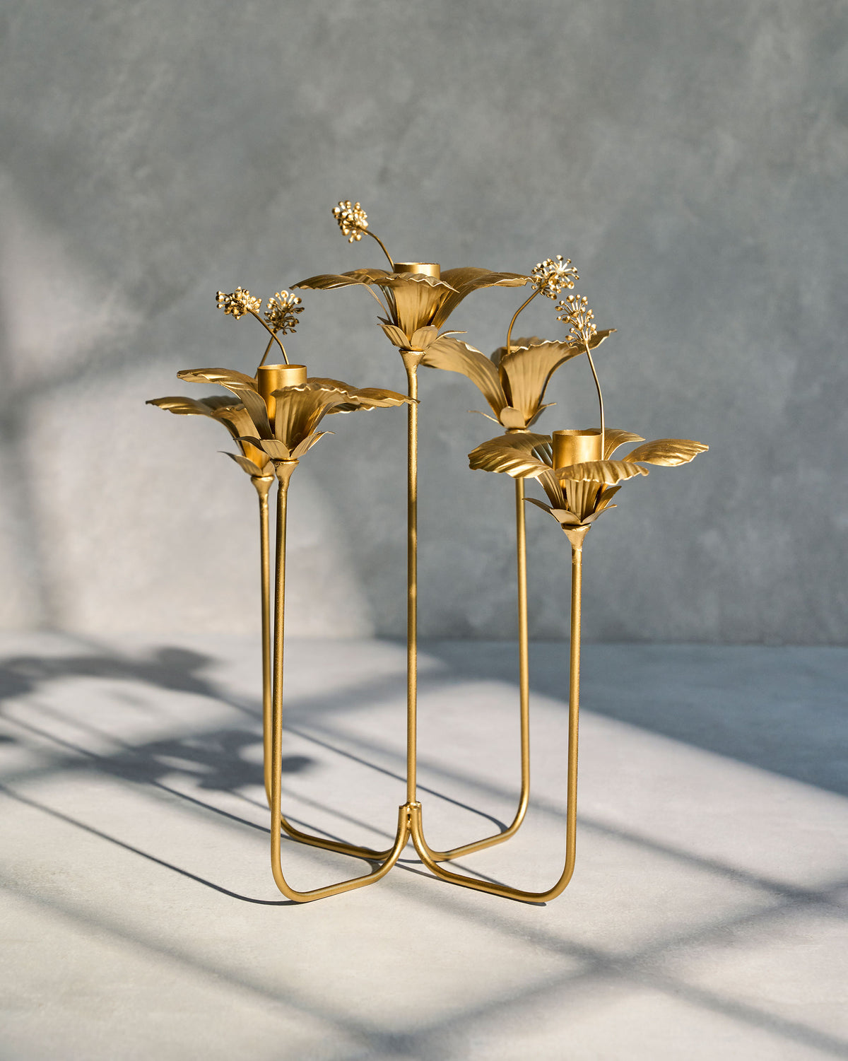 Gold hibiscus candle holder on a grey surface.