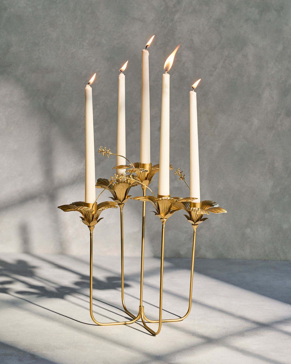 Gold hibiscus candle holder with five lit candles.