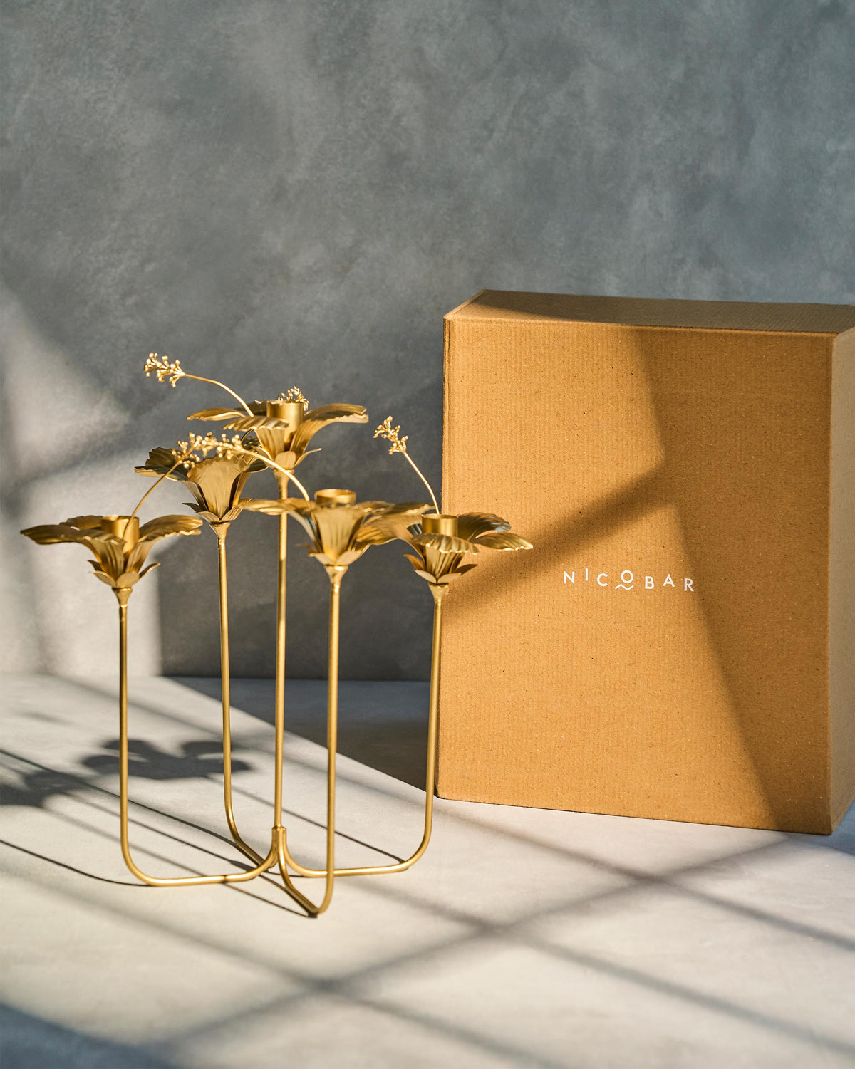 Gold hibiscus candle holder beside its Nicobar box.