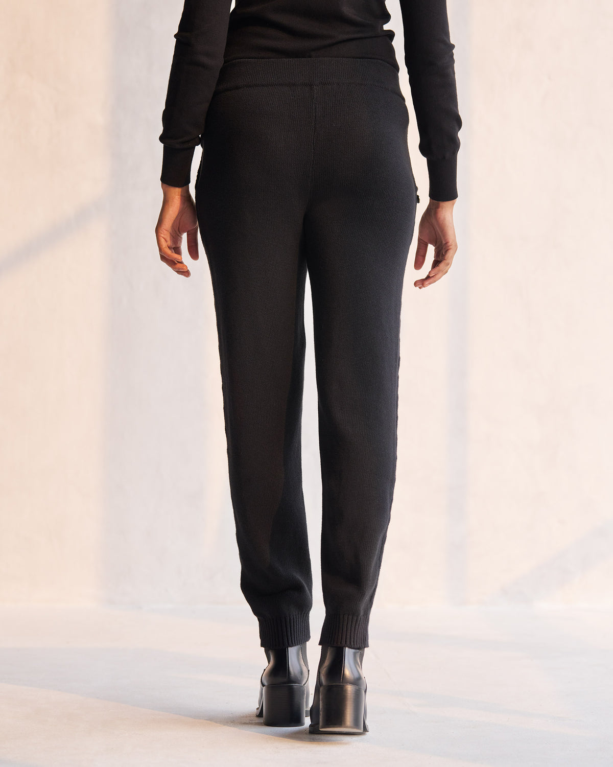 Back of black Pull-on Pants with ribbed ankle cuffs worn by a person.