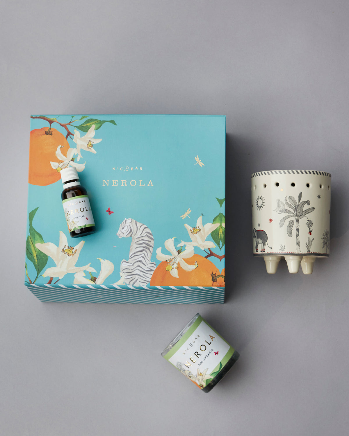 Azure gift set with an oil vial, soy candle and ceramic burner beside a turquoise box.