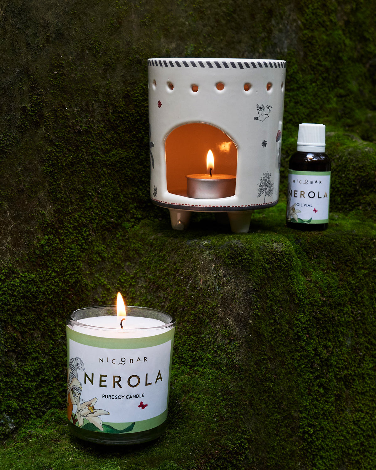 Lit ceramic burner with a tea light, oil vial and soy candle.