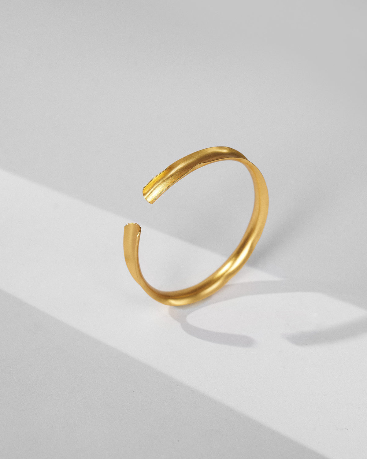 Thin gold Batur open cuff bangle with an organic wavy band.