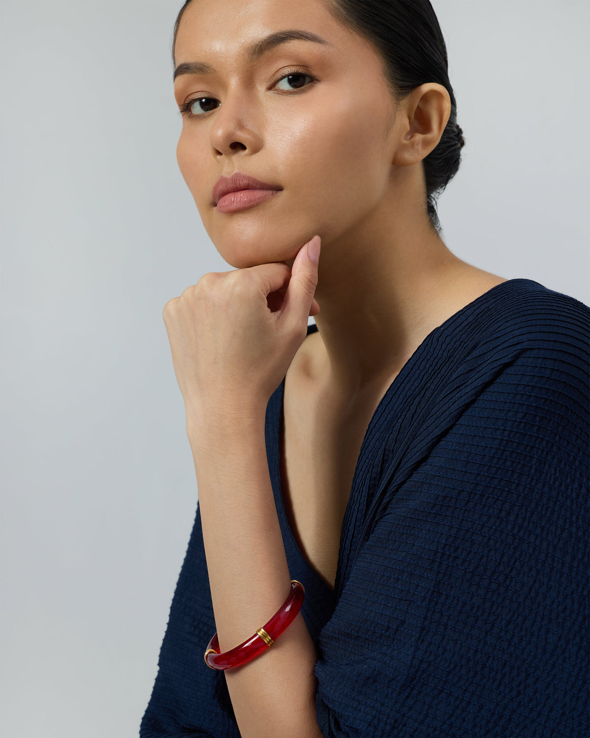 Translucent red glass bangle with gold accents worn on a wrist.