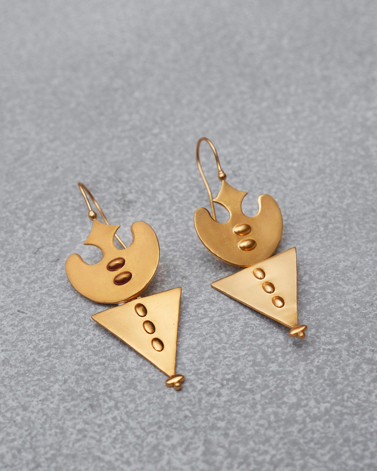 Pair of gold Lama Earrings laid flat.