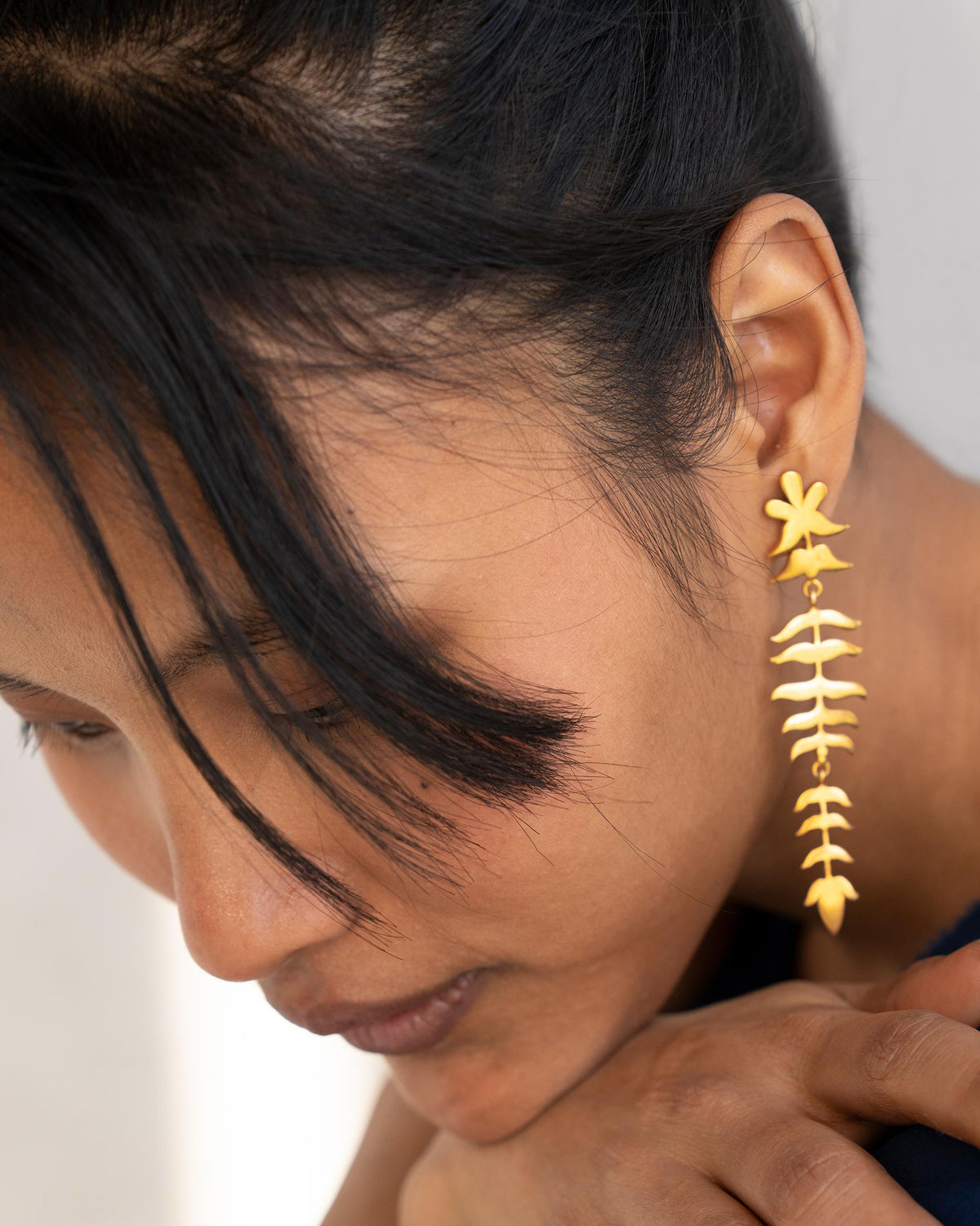 Side profile of Myra Earrings in gold worn by a person, showing their length.