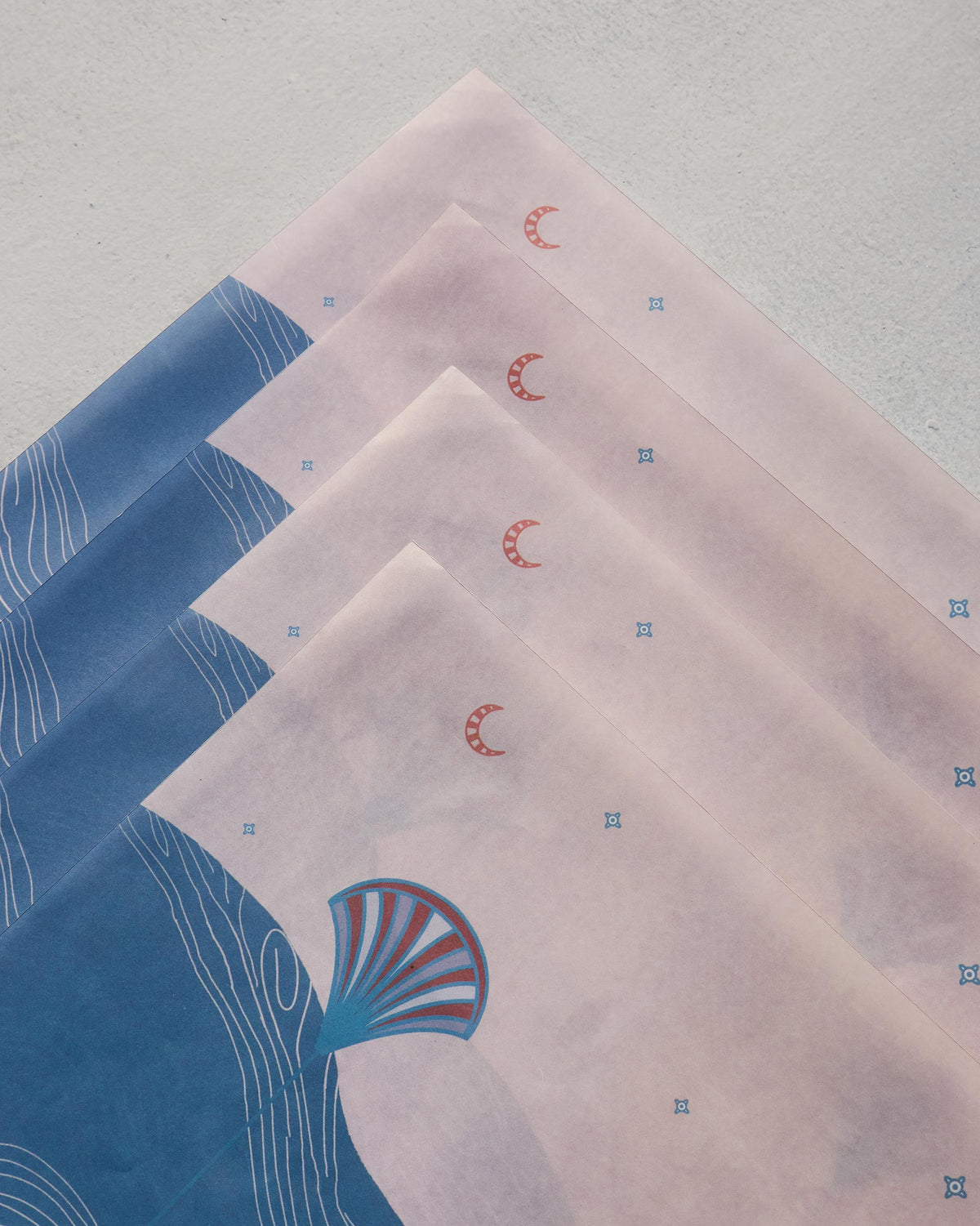 Close-up of Pacific Parchment paper rectangles fanned diagonally, showing crescent and dot prints.