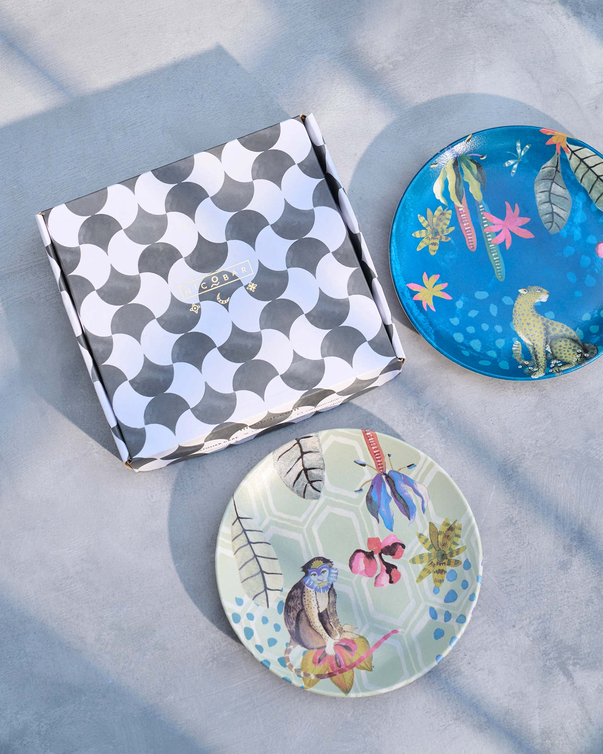 Pair of Mahi quarter plates with monkey and leopard prints beside gift box.