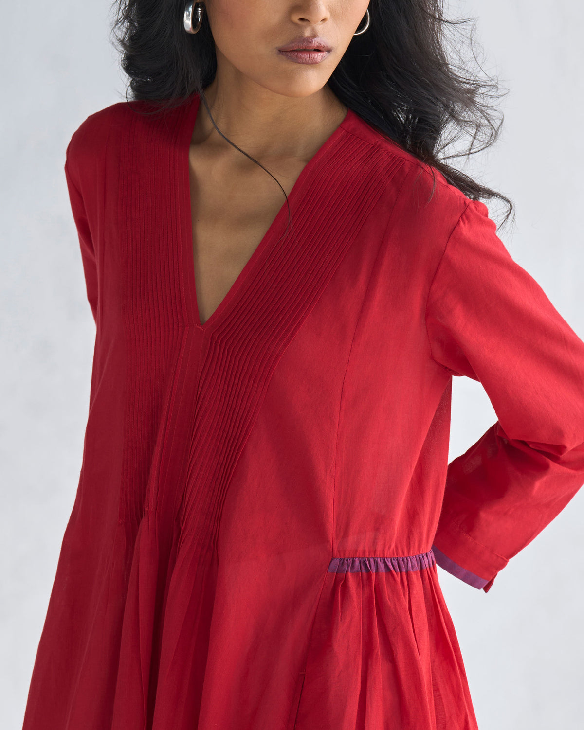 Close-up of a red Pintuck kurta showing vertical pintucks and purple waist piping.