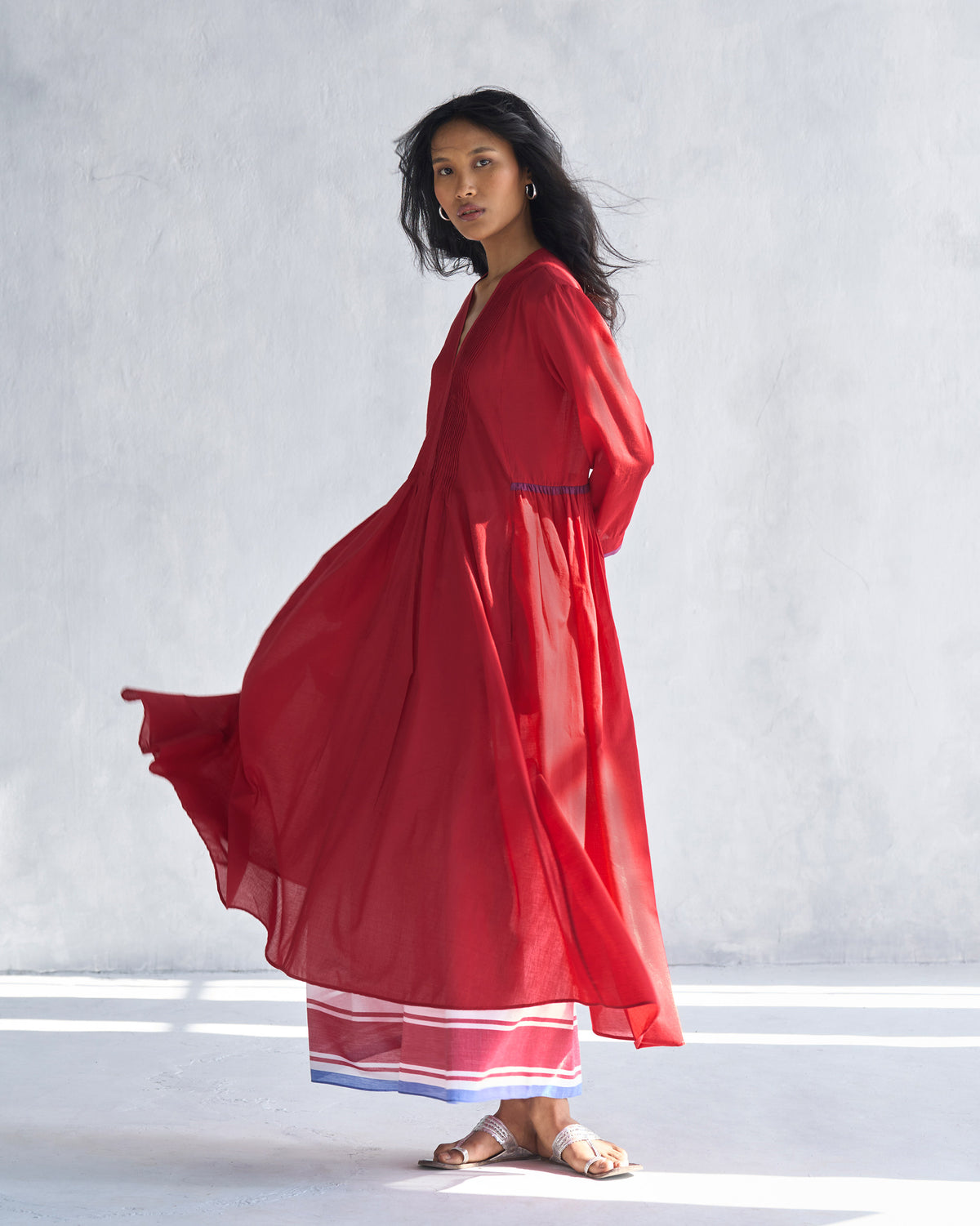 Side view of a red Pintuck kurta showing the sheer flared skirt in motion.