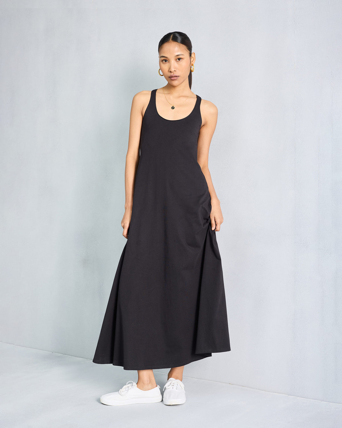 Person wearing a black sleeveless Esther dress with a scoop neck.