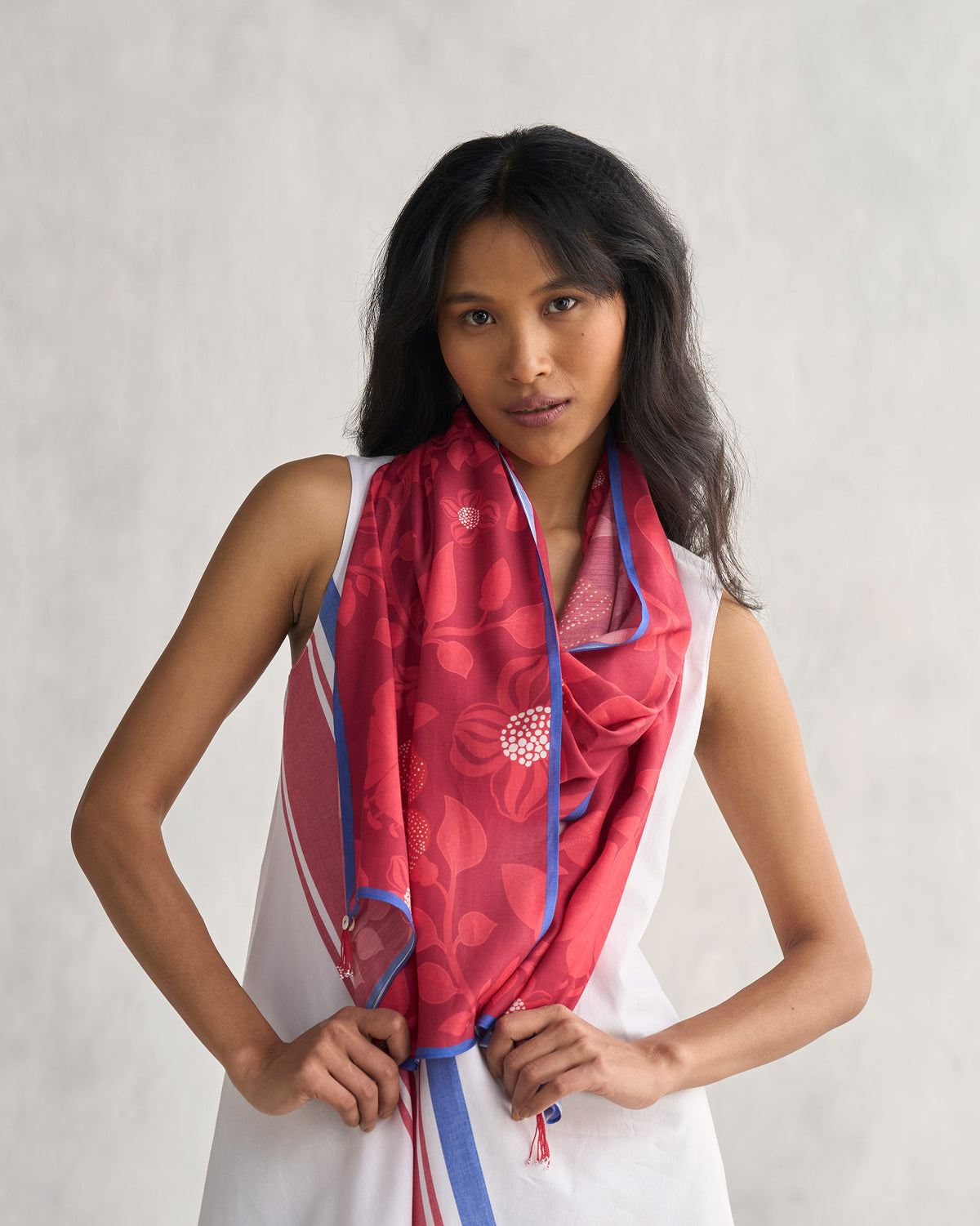 Person wearing a red Roseate scarf with blue edging and a tonal floral print.
