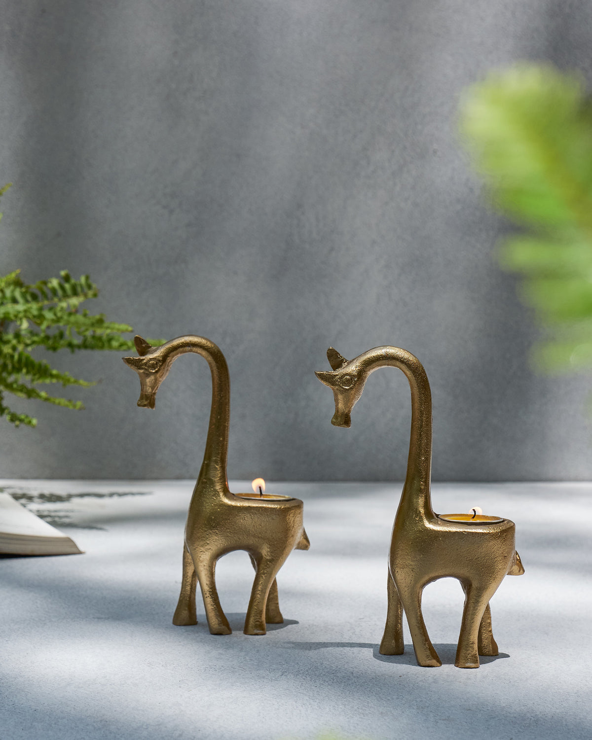 Pair of gold Giraffe Tealight Holders with lit tealights.