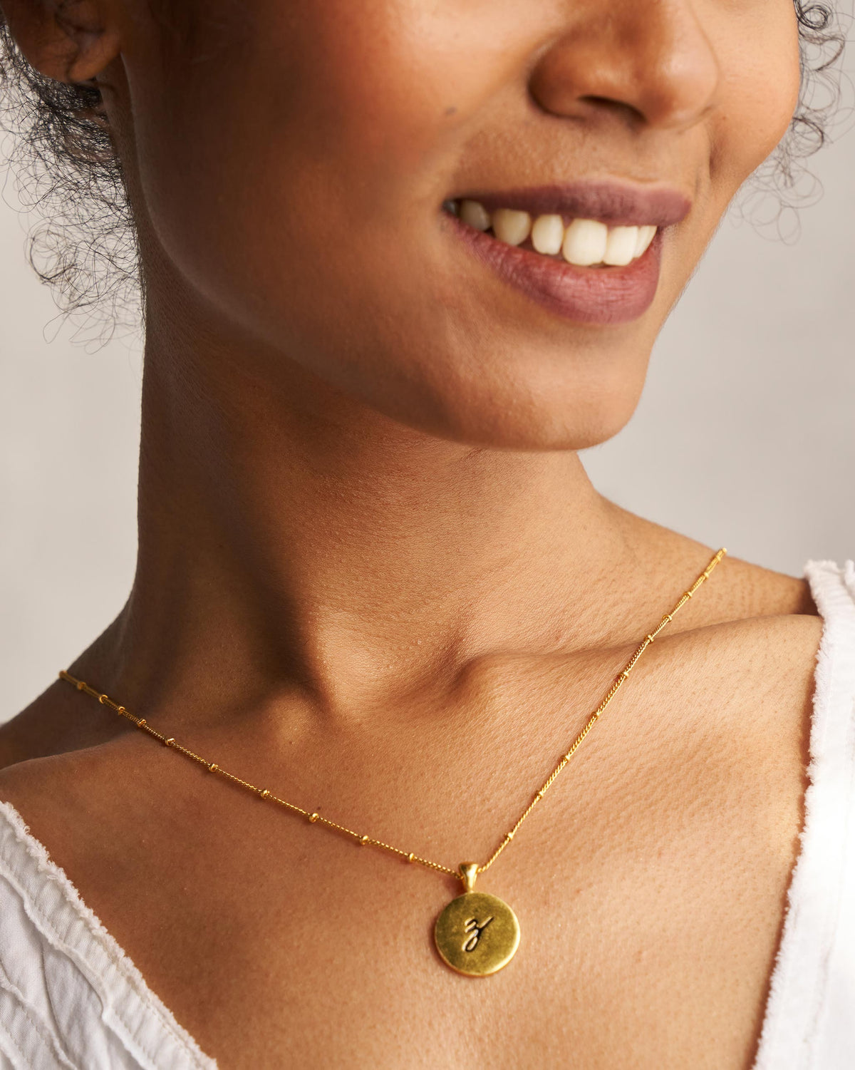 Gold Alphabet Z charm with a black script letter z when worn.