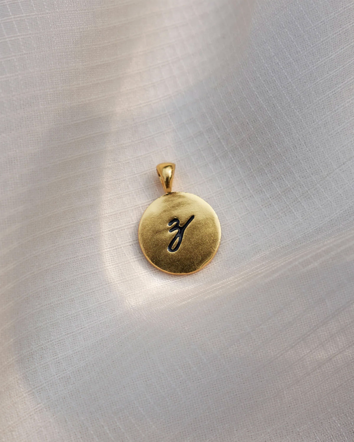Close-up of a gold Alphabet Z charm with a black script z.