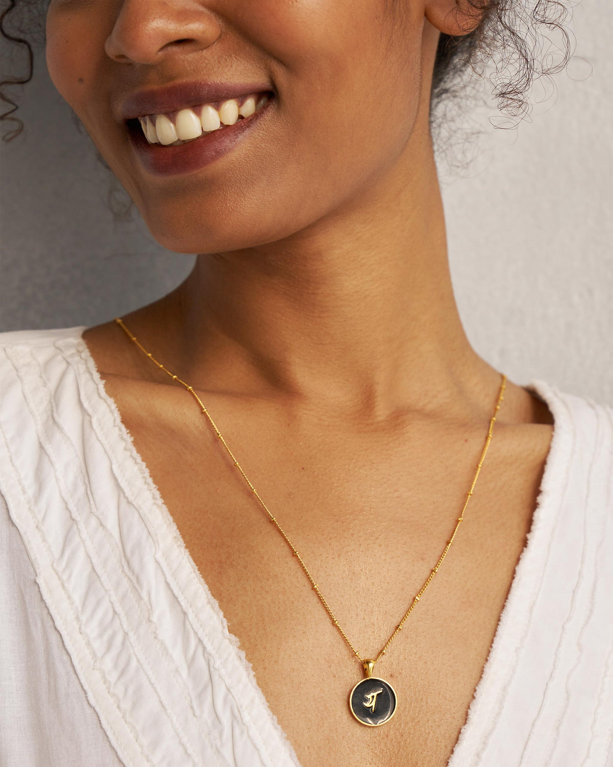 Black and gold Alphabet Y charm with य worn on a satellite chain.