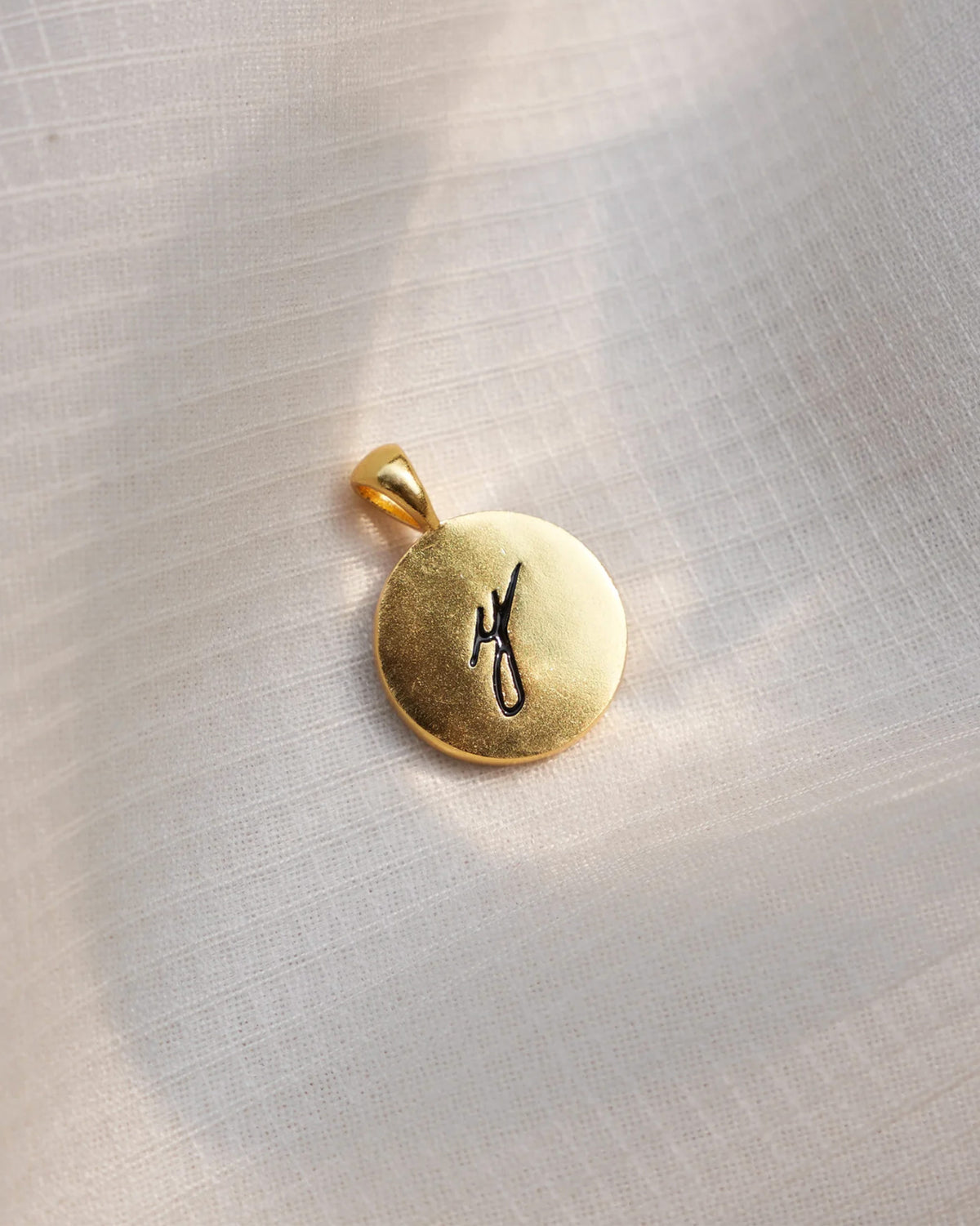 Close-up of a gold Alphabet Y charm with a black script y.