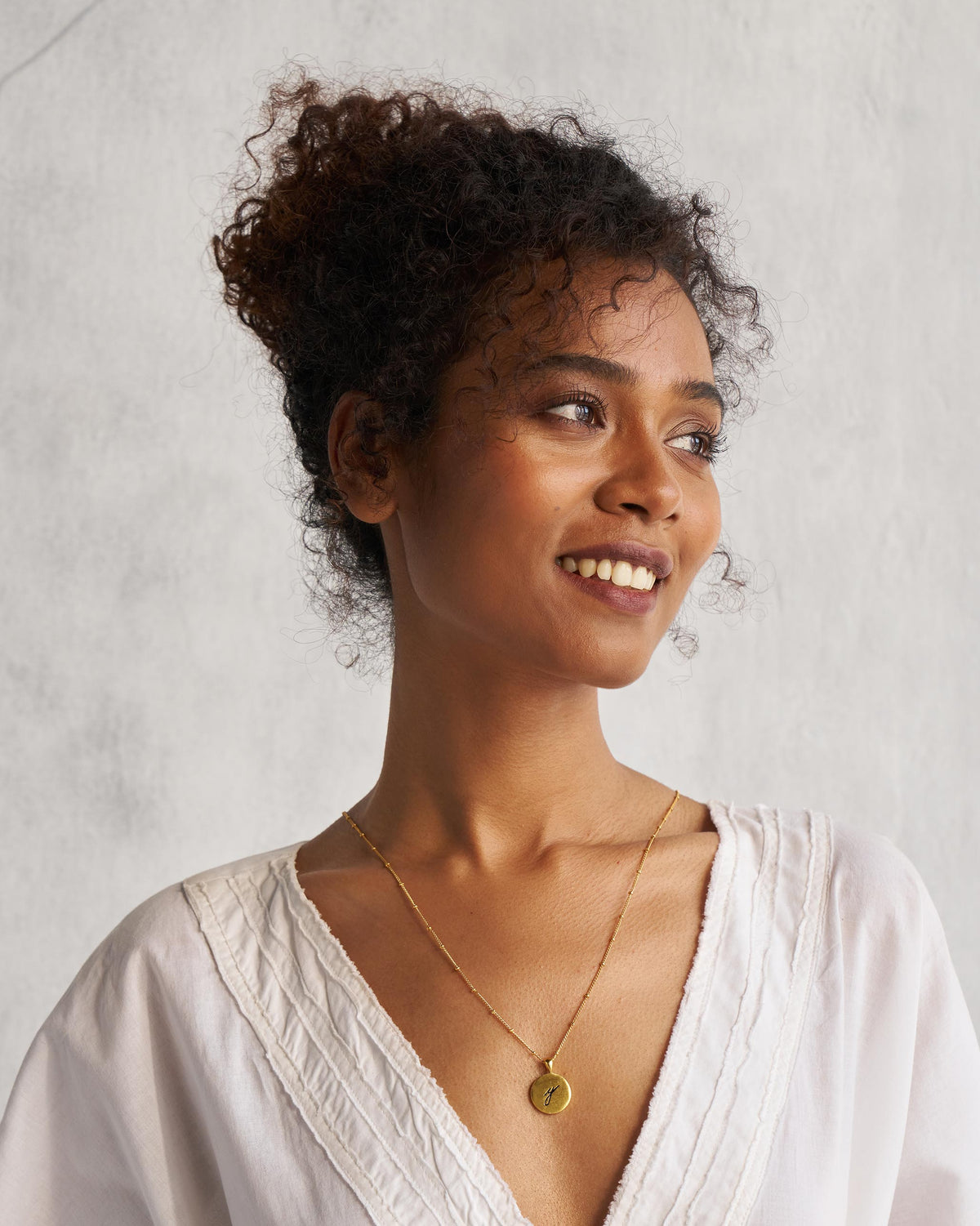 Person wearing a gold Alphabet Y charm on a fine chain.