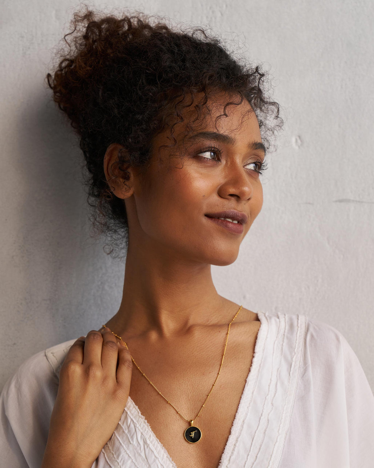 Person wearing a black and gold Alphabet Y charm necklace.