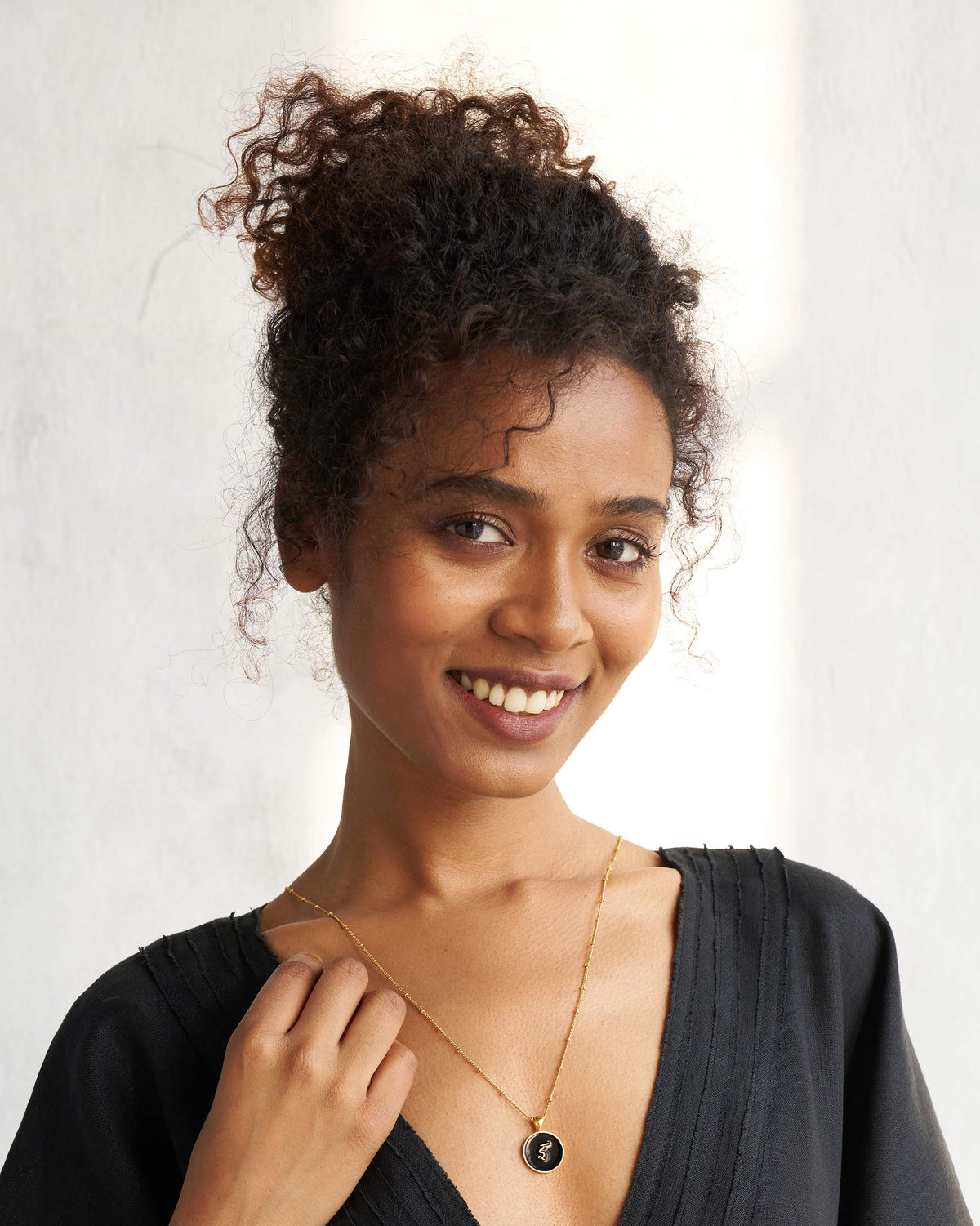 Person wearing a black and gold Alphabet I charm necklace.