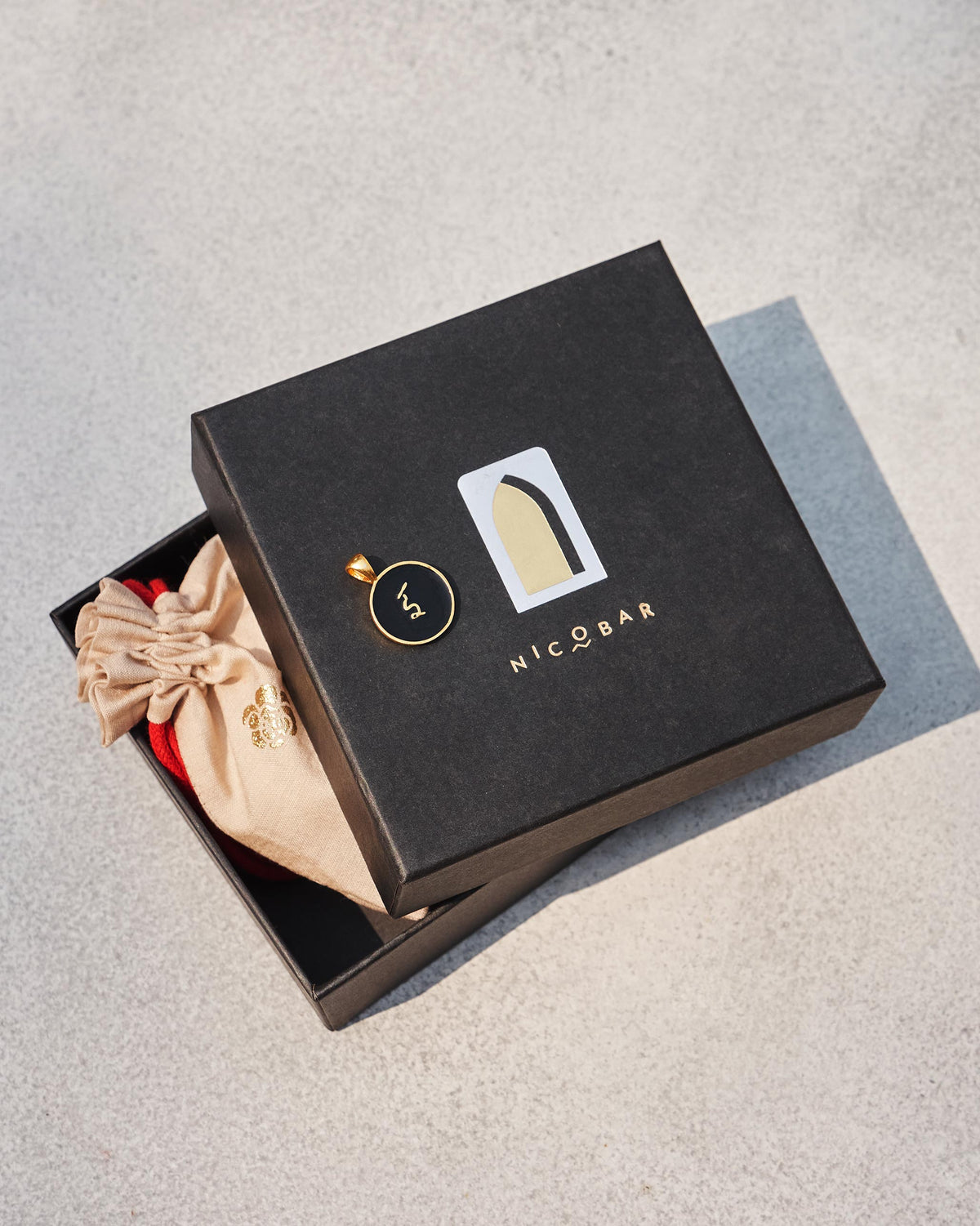 Black and gold Alphabet I charm on a Nicobar gift box.