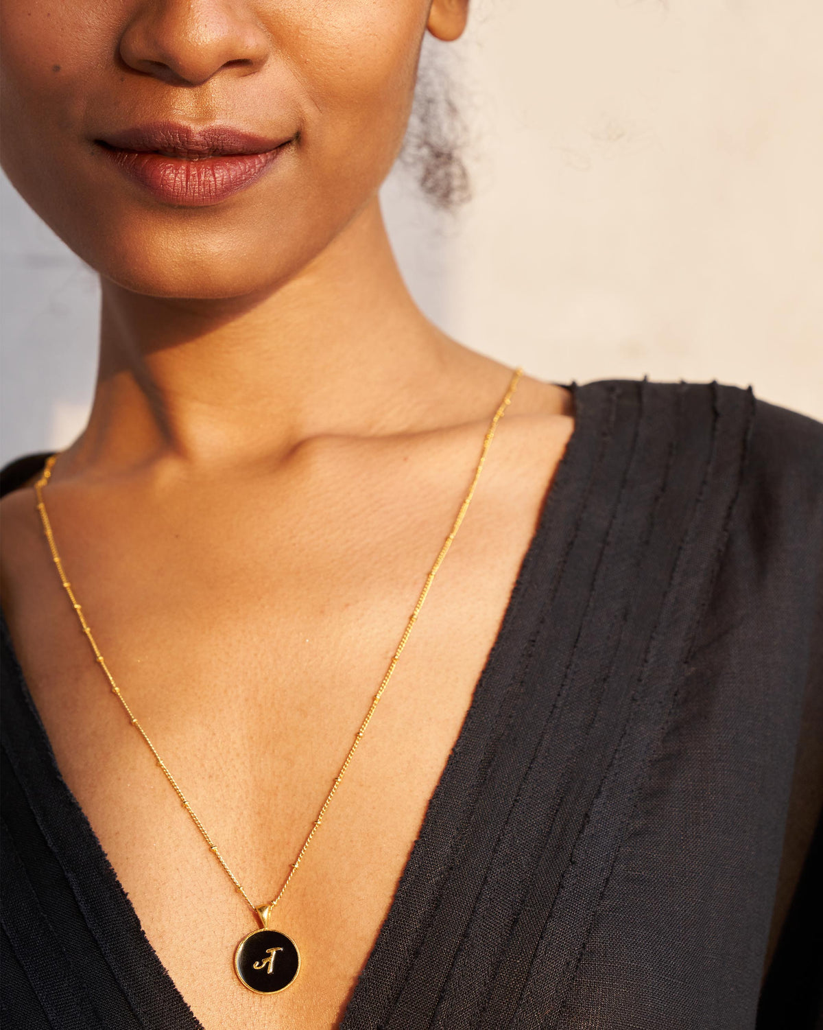 Black and gold Alphabet J charm with a Devanagari letter worn on a satellite chain.