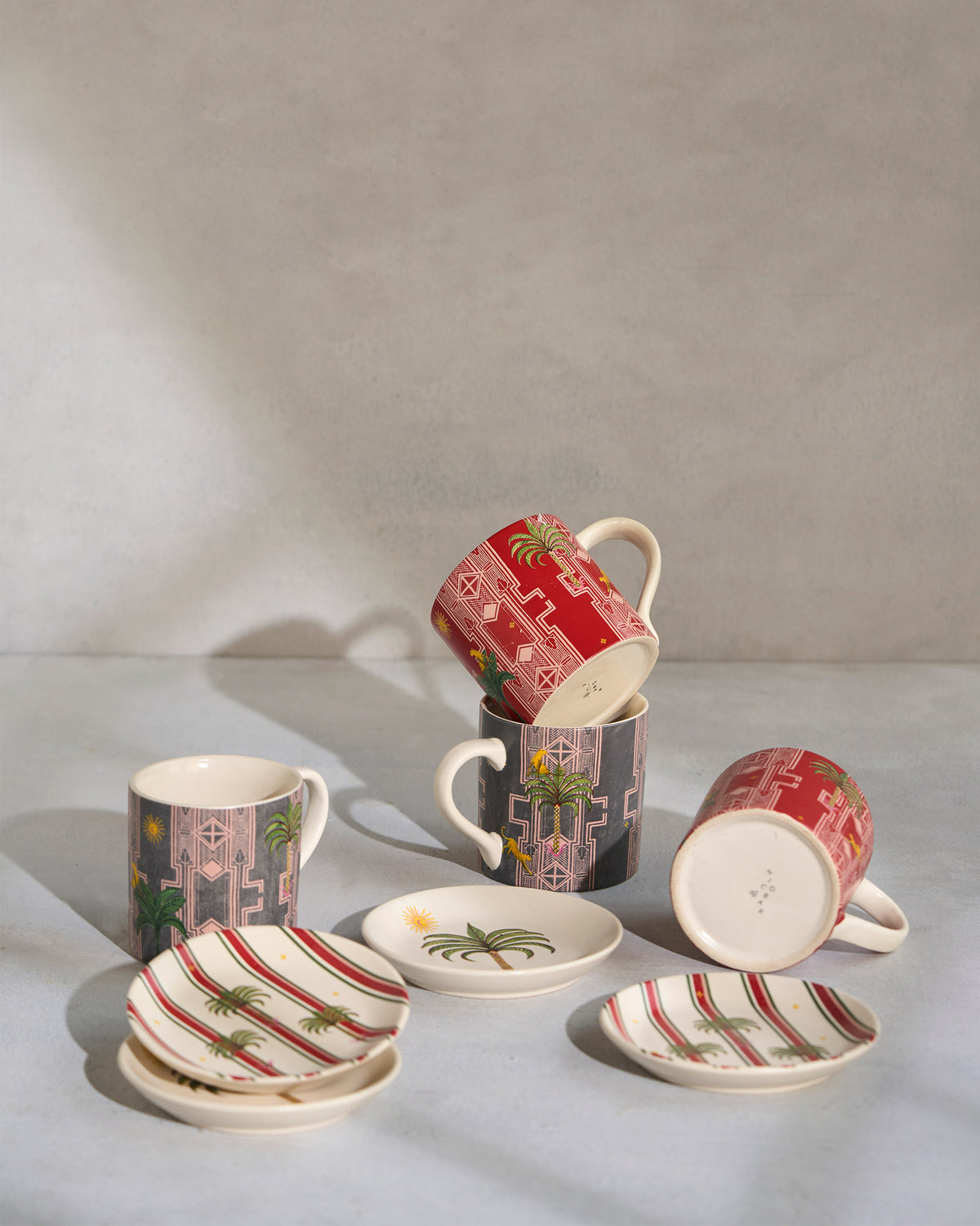 Leafy Affair red and charcoal mugs with palm plates arranged together.