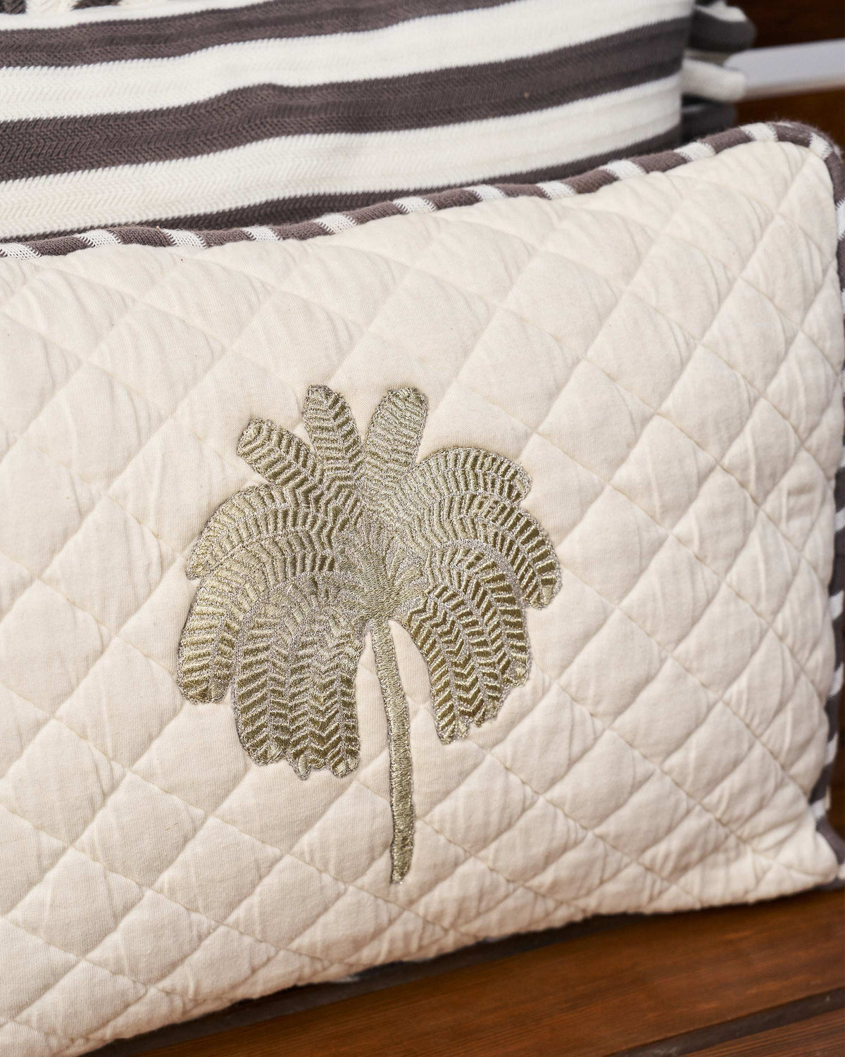 Close-up of Quilted Palm cushion embroidered palm on diamond quilting.