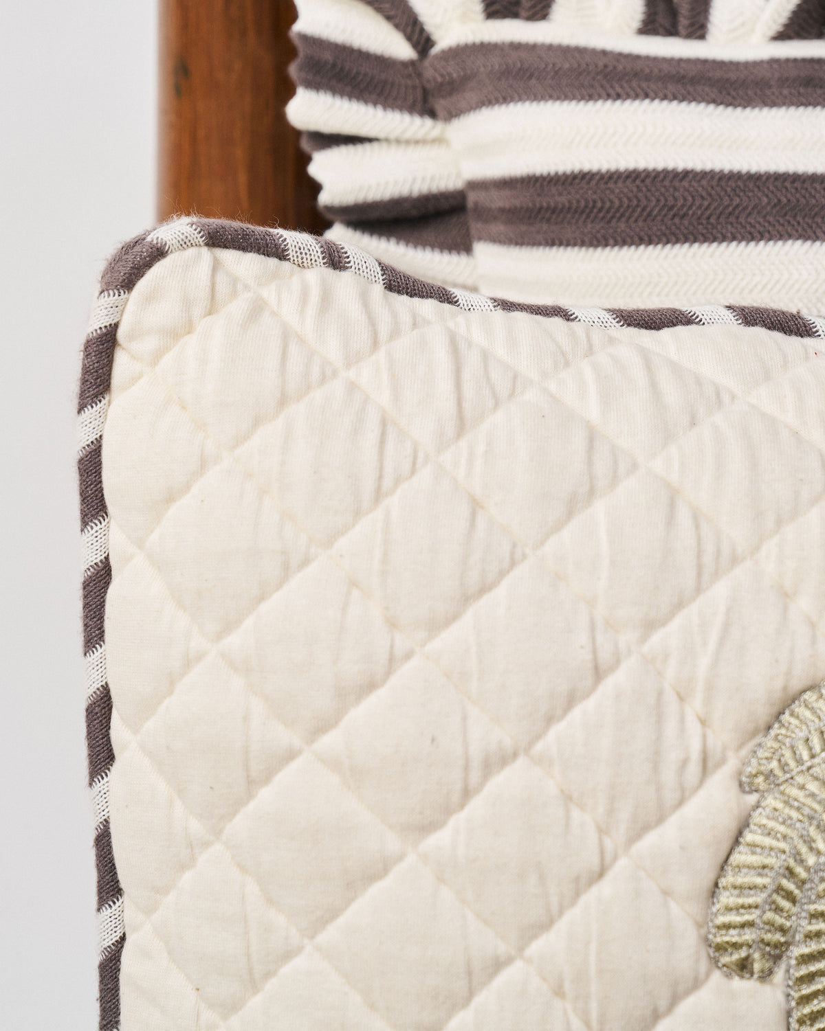 Close-up of Quilted Palm cushion quilting and striped piping edge.