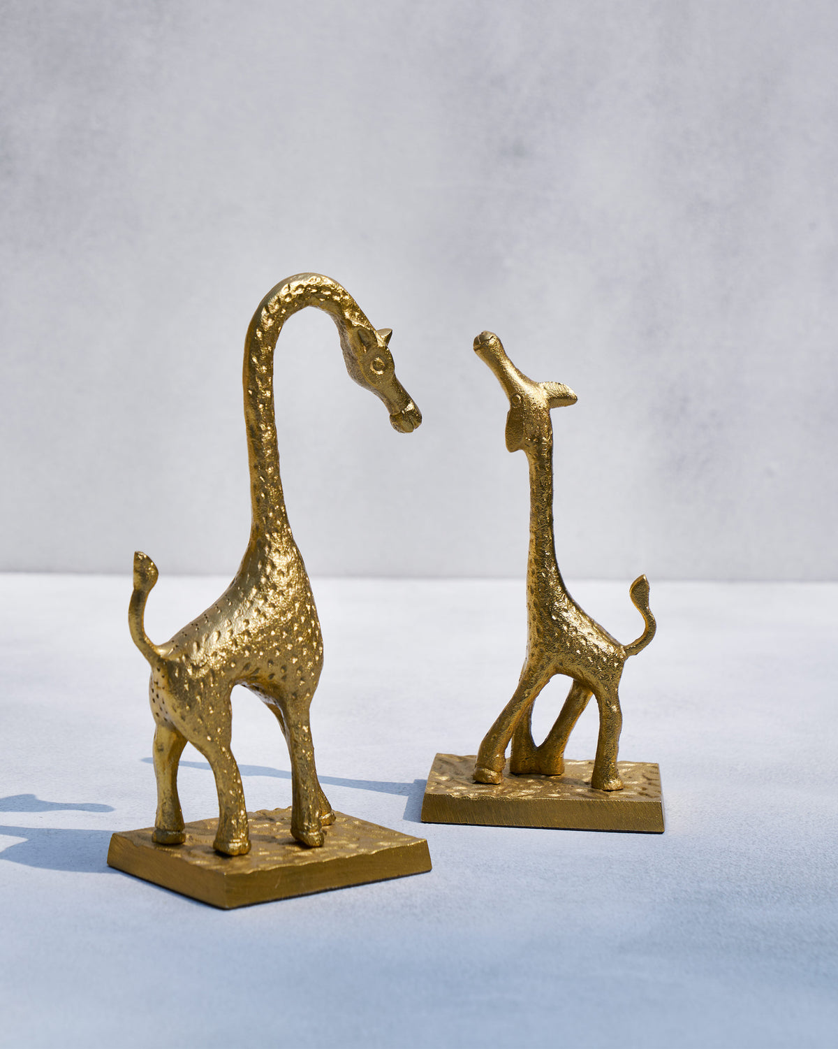 Giraffe bookends facing each other in textured gold on square bases.