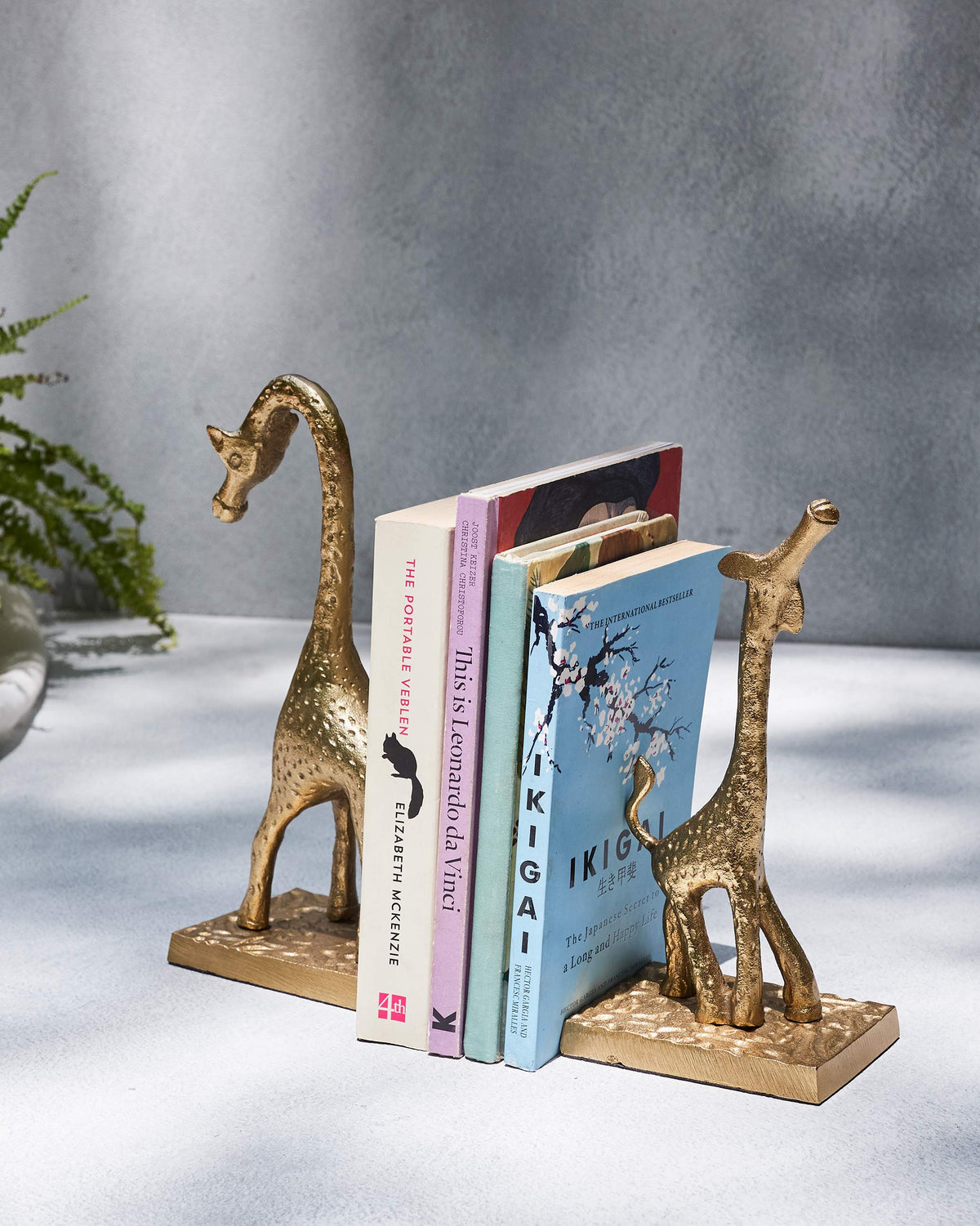 Giraffe bookends holding a short stack of books upright between them.