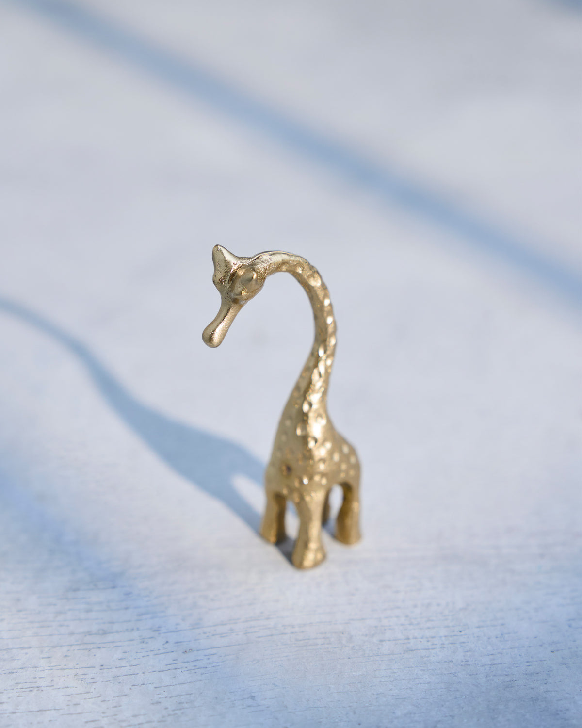 Giraffe Menu Card Holder in brass with its neck curved upward.