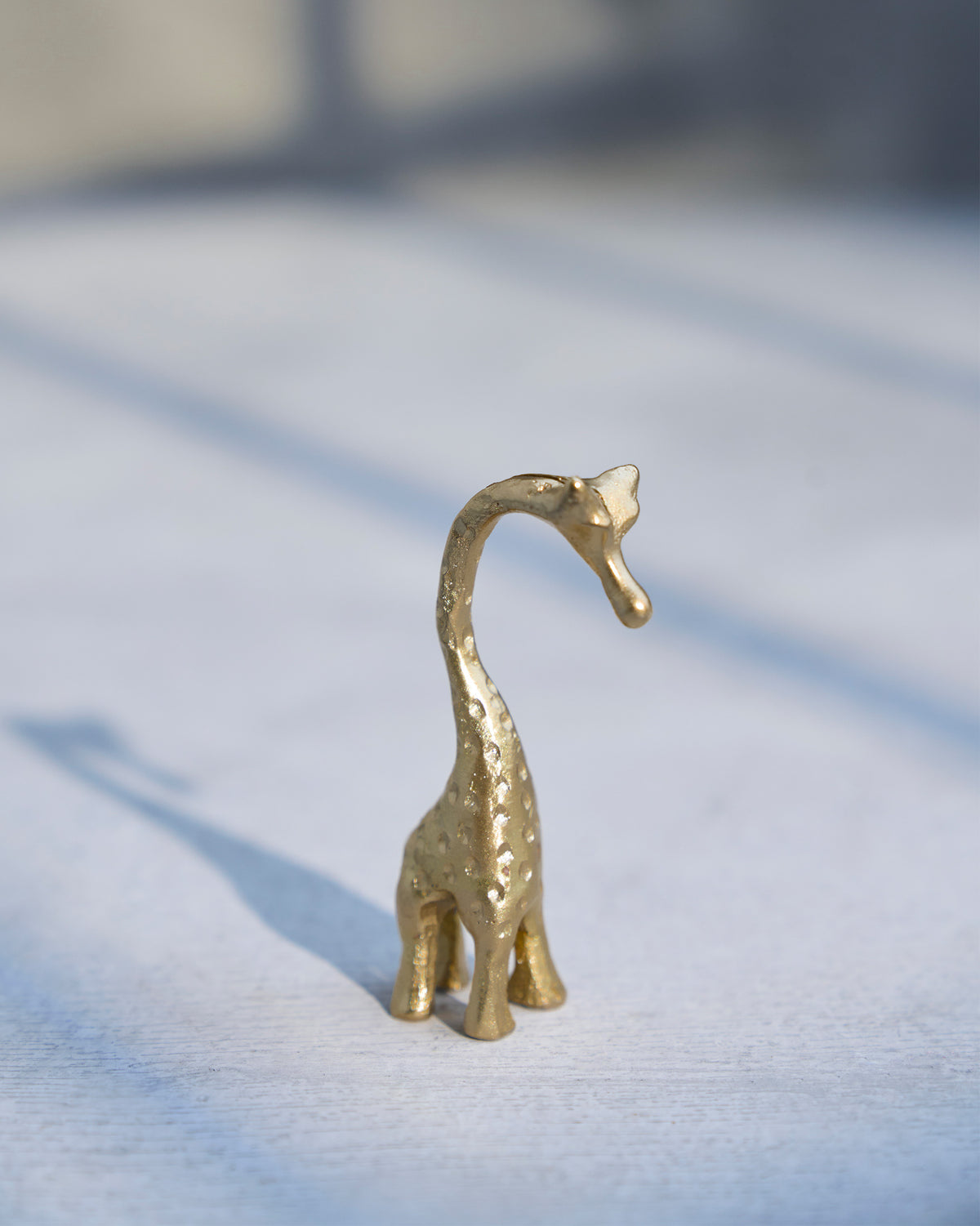 Giraffe Menu Card Holder in brass, seen from the back with its neck curved.