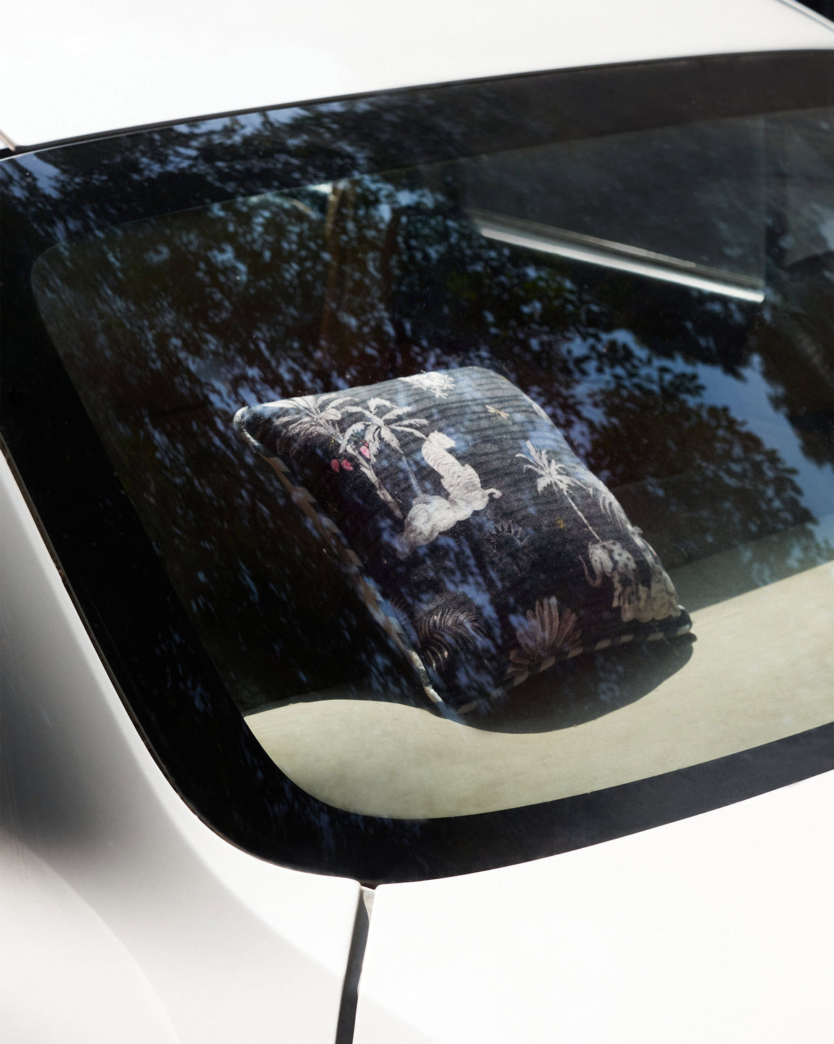 Charcoal Ele Car Cushion placed in a car, with its elephant and palm print visible.