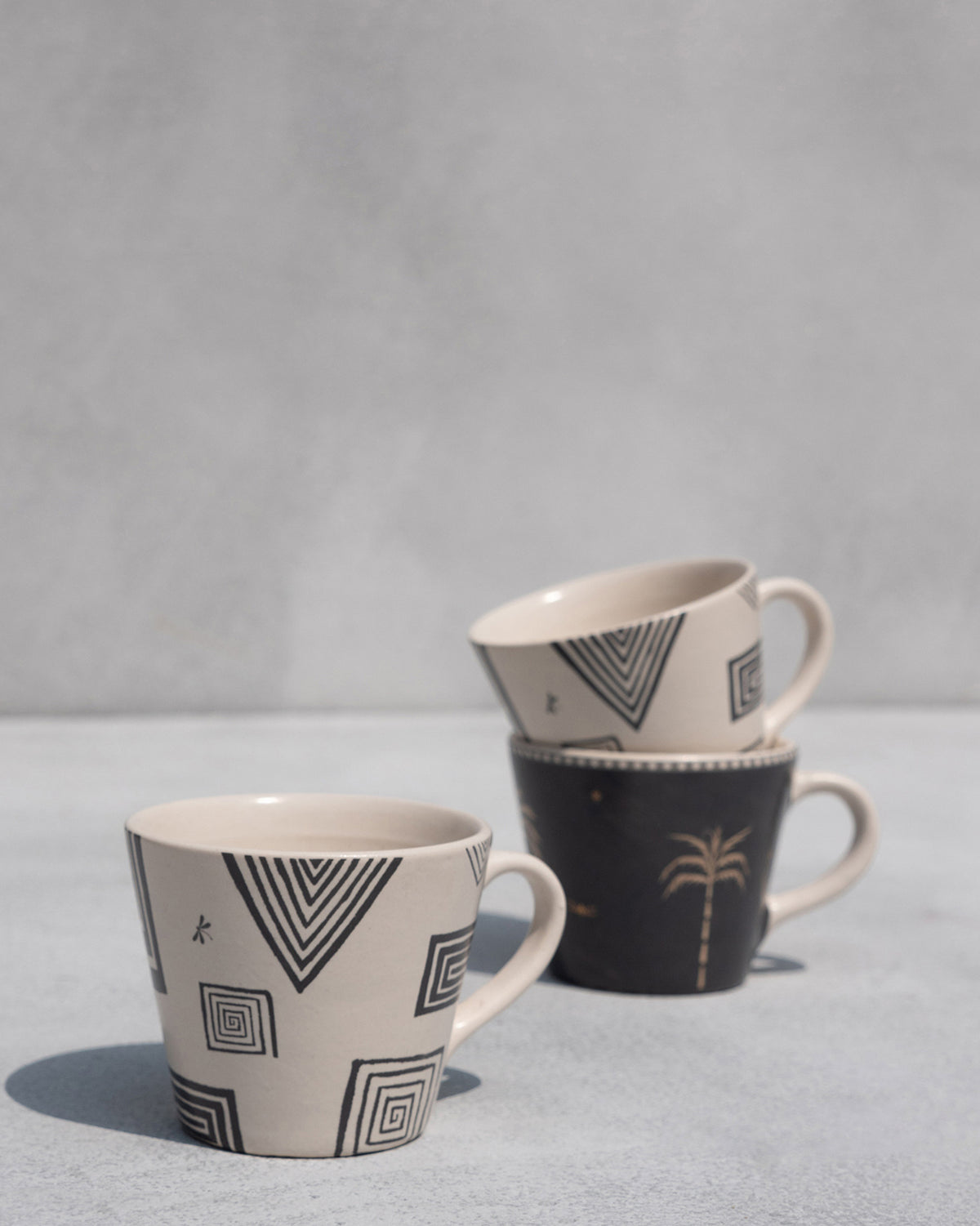 Serenity espresso mugs showing black geometric and gold palm designs.