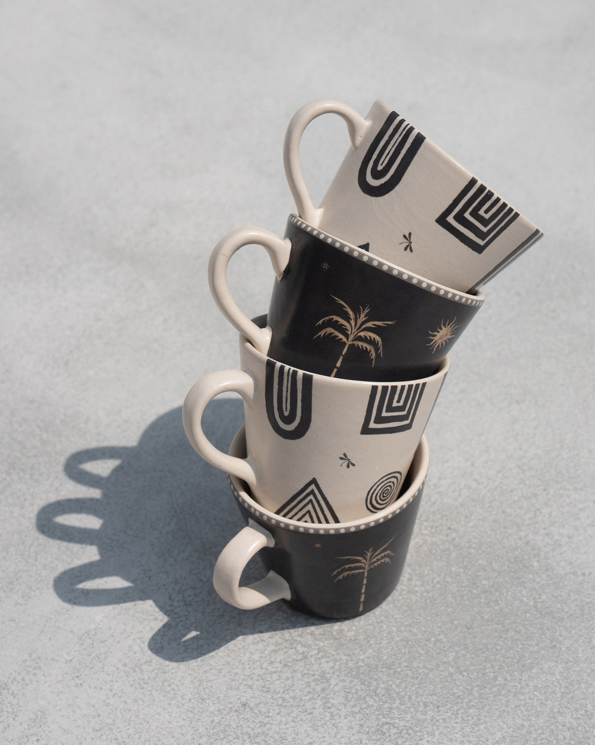 Stack of four Serenity espresso mugs with geometric and palm prints.