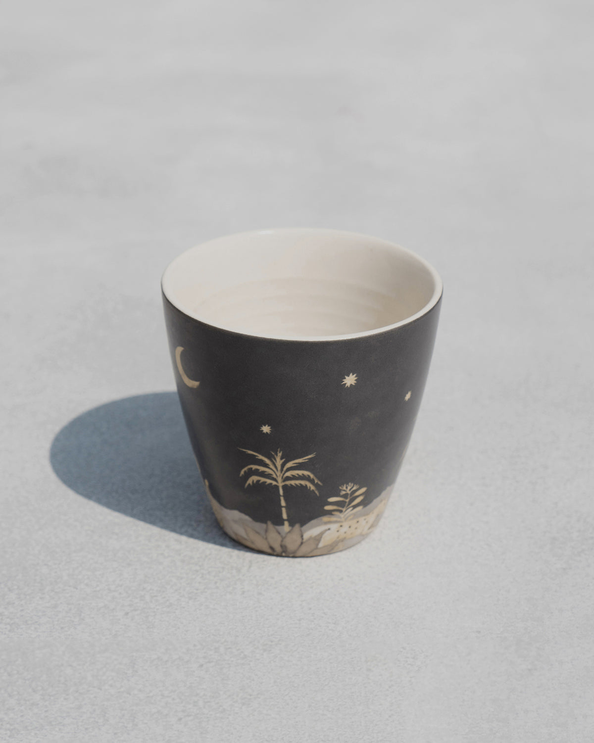 Zuri Conical Mug showing a palm tree and stars on a charcoal finish.