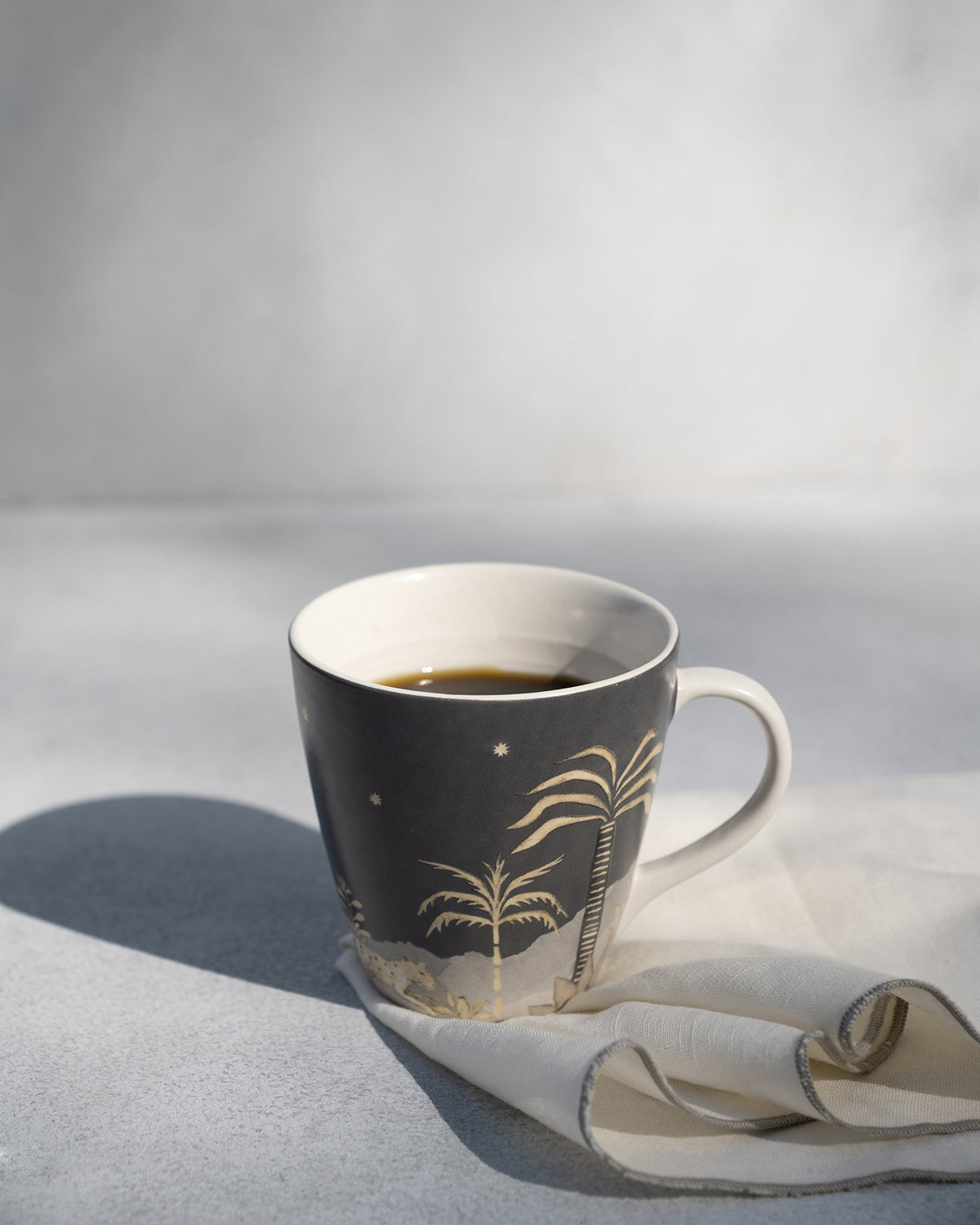 Zuri Conical Mug filled with coffee, showing palm tree motifs.