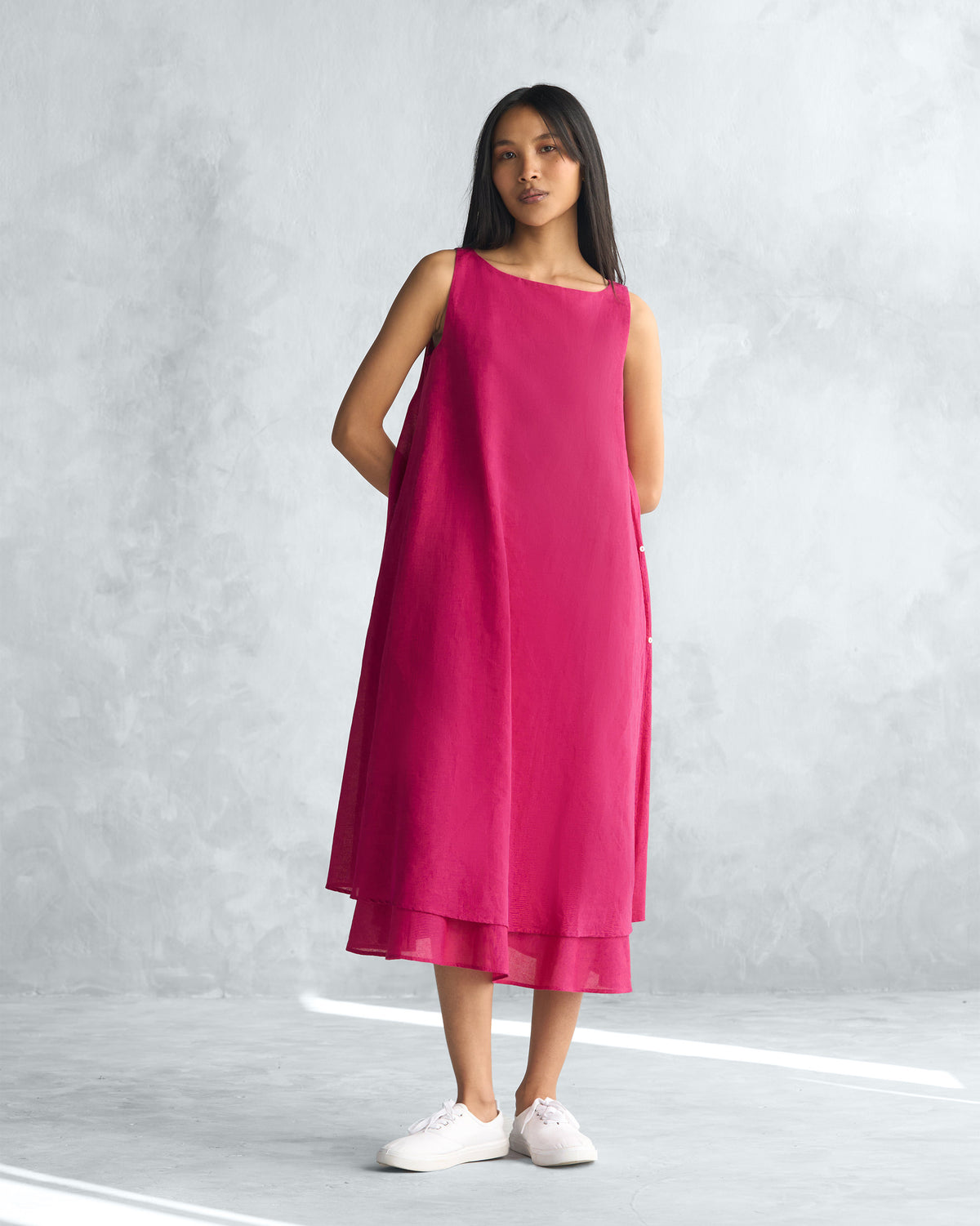Person wearing a sleeveless pink Double layer dress with a layered hem.