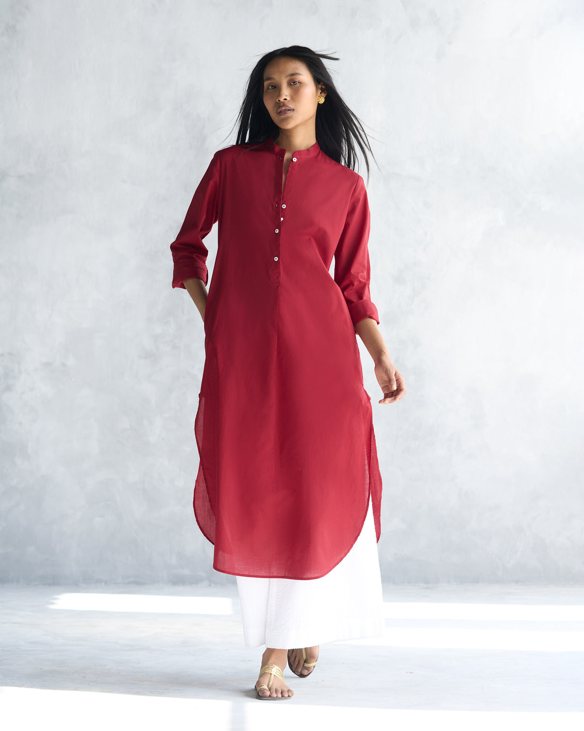 Person wearing a red long kurta with a mandarin collar and curved hem.