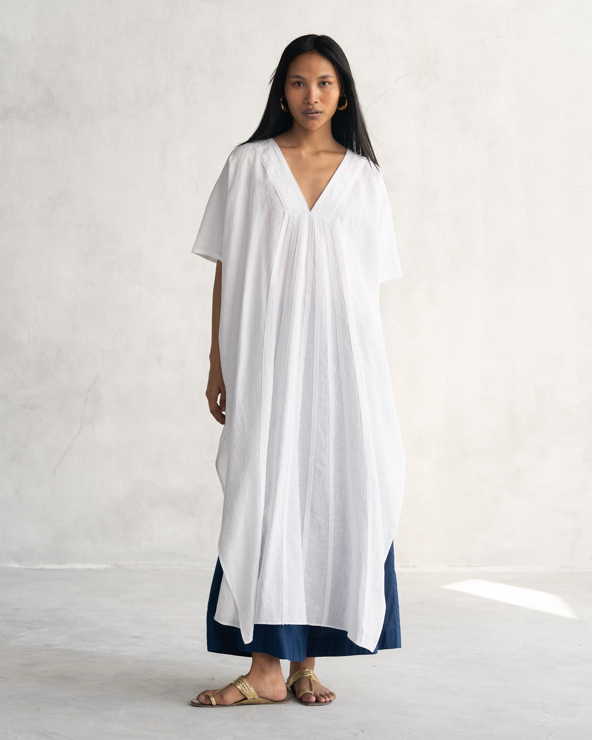 Person wearing a white Tulum kaftan with a deep V-neck.