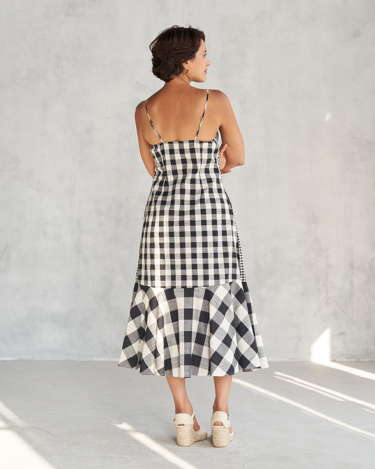 Back of an ivory and black check strappy midi dress with a ruffled hem.
