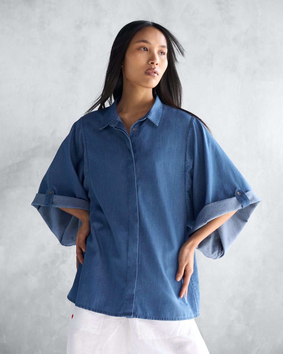 Person wearing a blue Drop Armhole Shirt with rolled sleeves.
