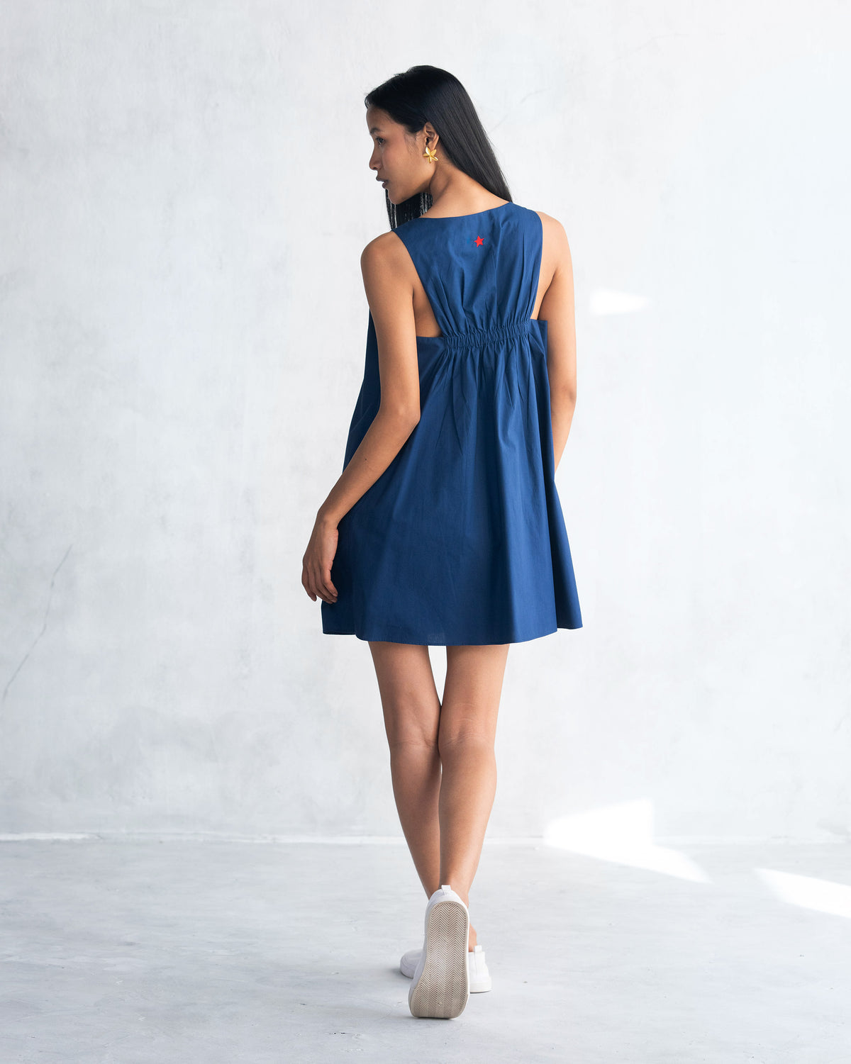 Back of a navy short racerback dress worn by a person.