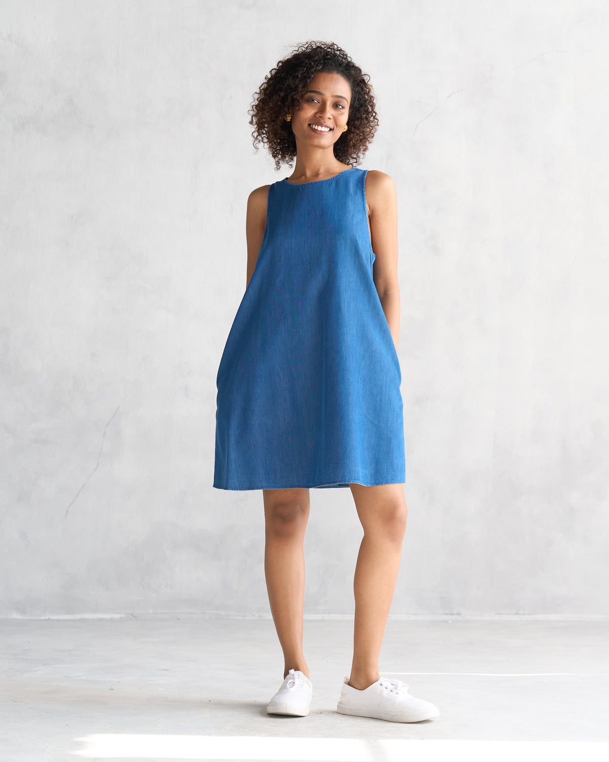Person wearing a blue short racerback dress with a sleeveless A-line shape.